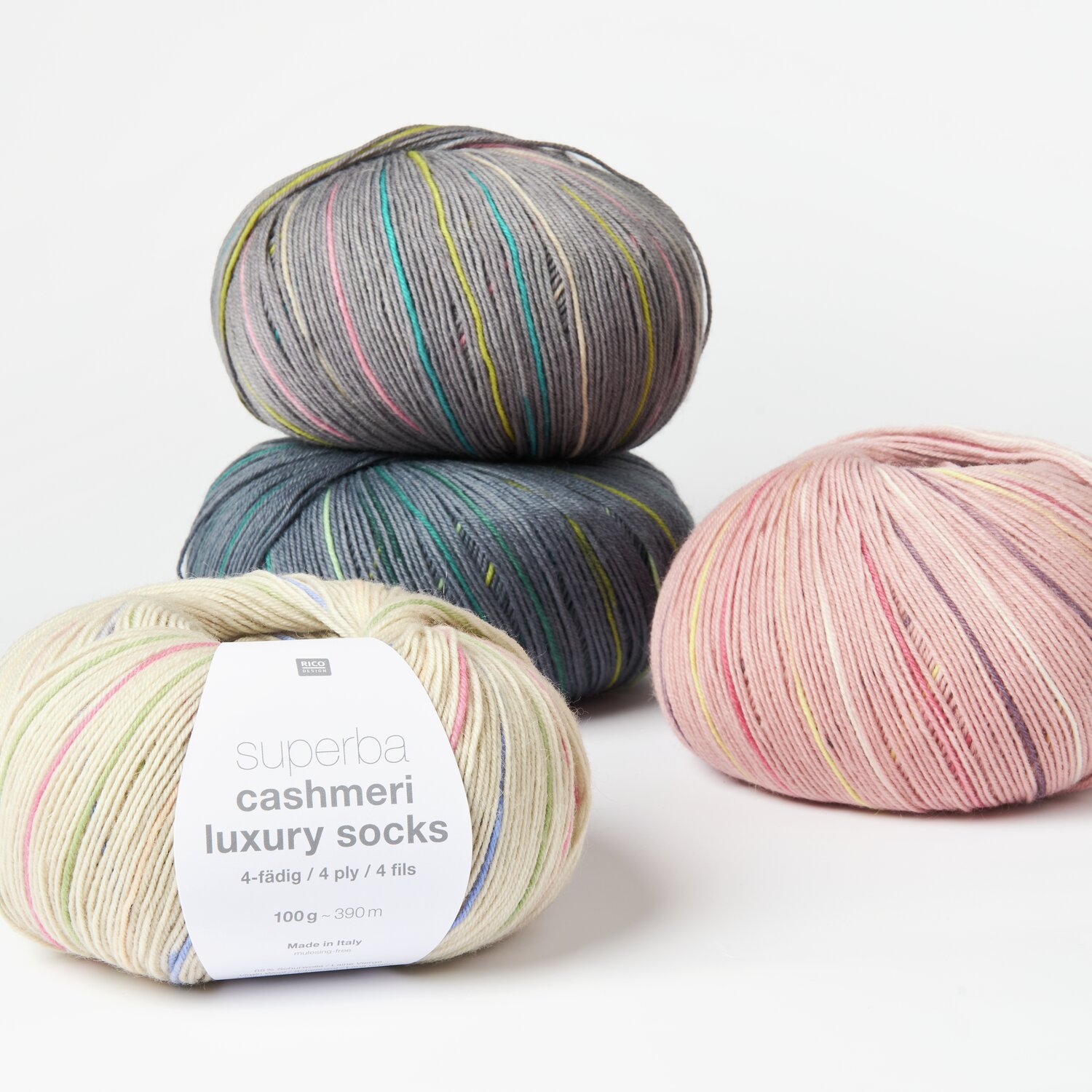 Superba Cashmeri Luxury Socks 4fädig: Drei Wollknäuel in Pastell- und Grautönen, ideal für hochwertige Strickprojekte.