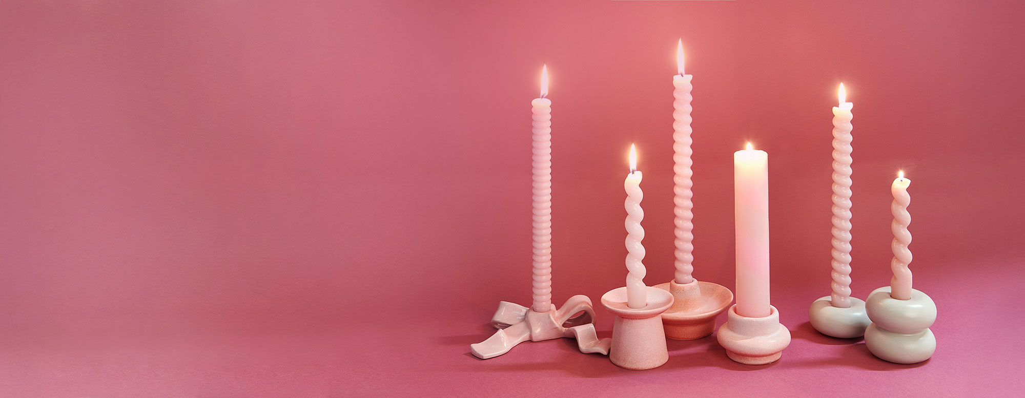 verschiedene rosa Stabkerzen stehen in Kerzenhaltern