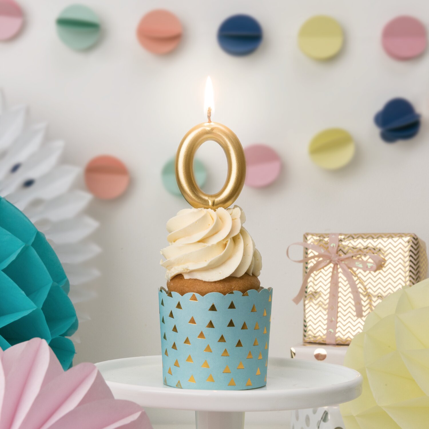 Zahlenkerze Gold von Rico Design steckt auf Cupcake mit Creme-Topping, dekoriert mit Partygirlanden und Geschenkbox im Hintergrund für festliche Anlässe