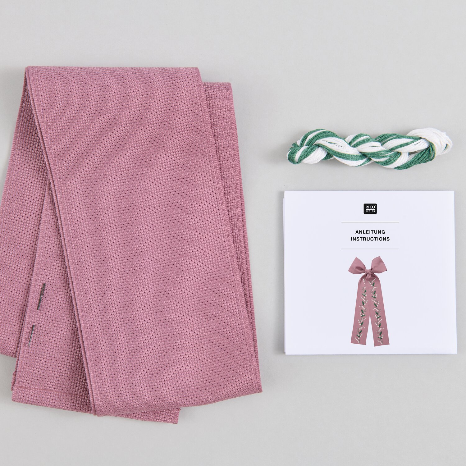 Stickpackung Gezählter Kreuzstich Schleife Maiglöckchen mit rosa Stoff, Garn und Anleitung von Rico Design. Ideal für kreative Handarbeiten.