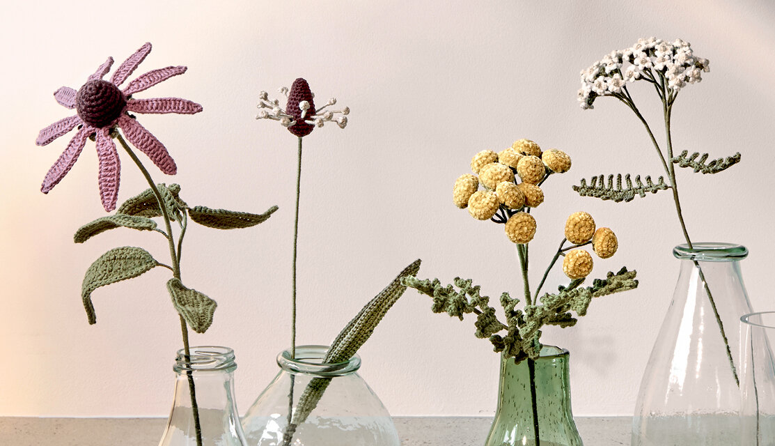 Material Ricorumi In the Meadow Spitzwegerich, gehäkelte Wiesenblumen in Glasvasen auf heller Fläche, ideal zur dekorativen Präsentation von Handarbeitsprojekten