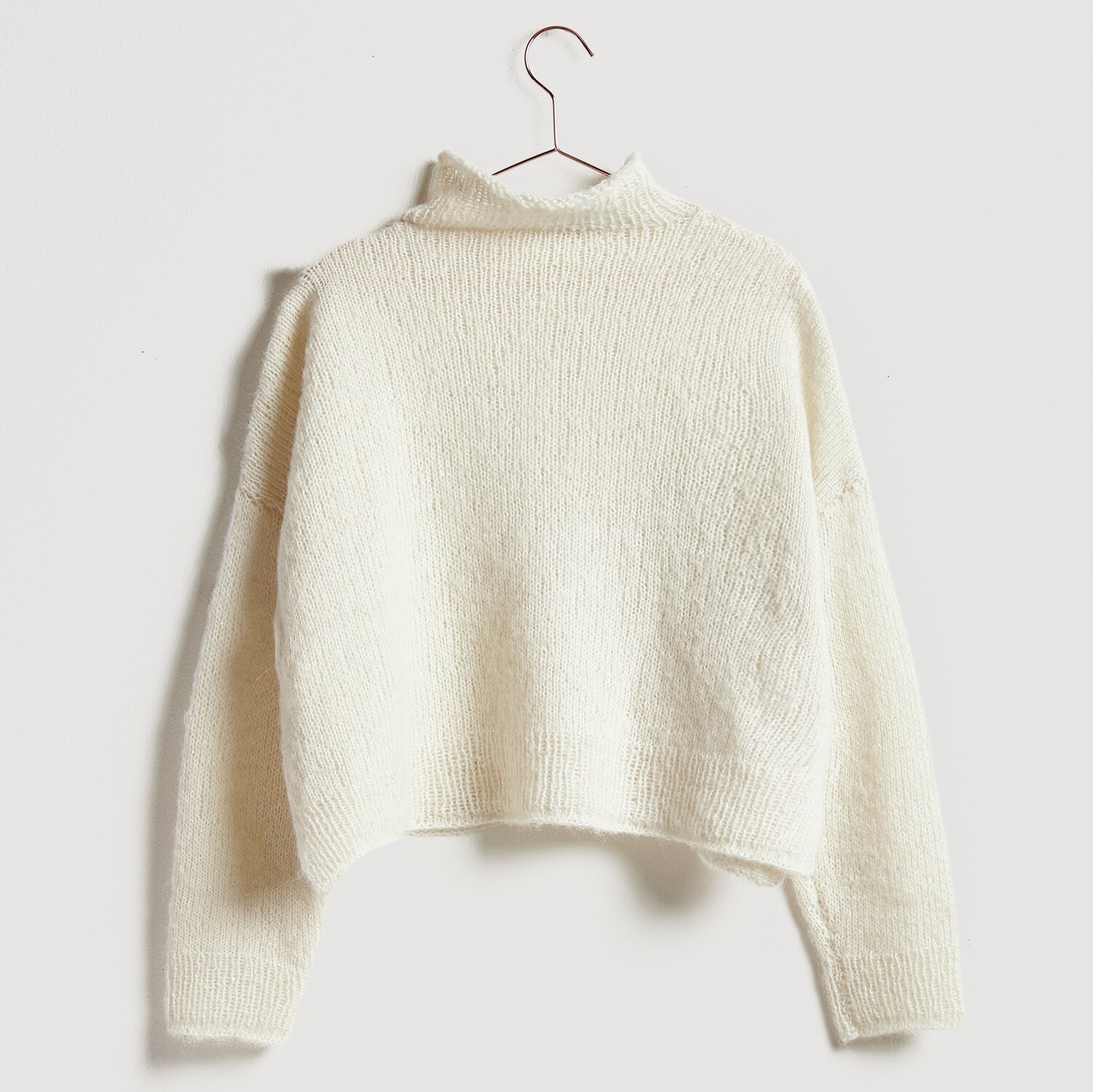 Die Neue Masche No. 13 Herbst von idee. Creativmarkt Luxury Alpaca Cotton Fusion Pullover in Creme, gestrickt aus weicher Wolle, hängt an einem Kleiderbügel.