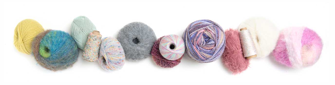 Reihe kleiner Garnknäuel und Wollproben in Gelb, Grün, Blau, Grau, Rosa und Weiß