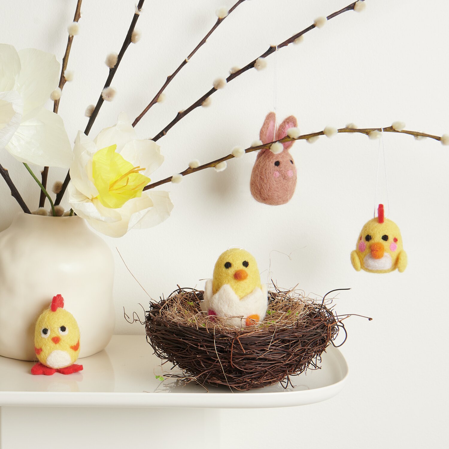 Aufhänger Filz-Osterfiguren 3D 4 Stück: Gelbe Küken und rosa Hase aus Filz, dekorativ an Zweigen und Nest arrangiert.