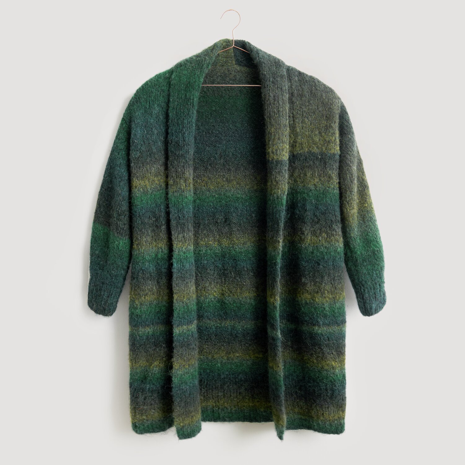 Lovewool No. 21 Herbst-Winter Sprachauswahl deutsch von Rico Design Strickjacke in Grün- und Blautönen, hängend an einem Kleiderbügel. Modell Legeware, ideal für kühle Tage. Weiches Material, perfekt für gemütliche Anlässe.