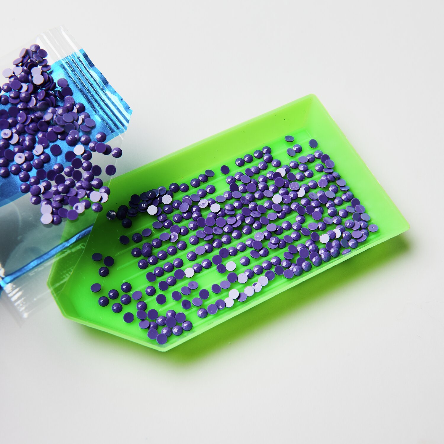 Diamond Painting DIY-Set Funkelnder Blumenkranz: Lila Glitzersteine auf grünem Tablett, ideal für kreative Bastelprojekte.