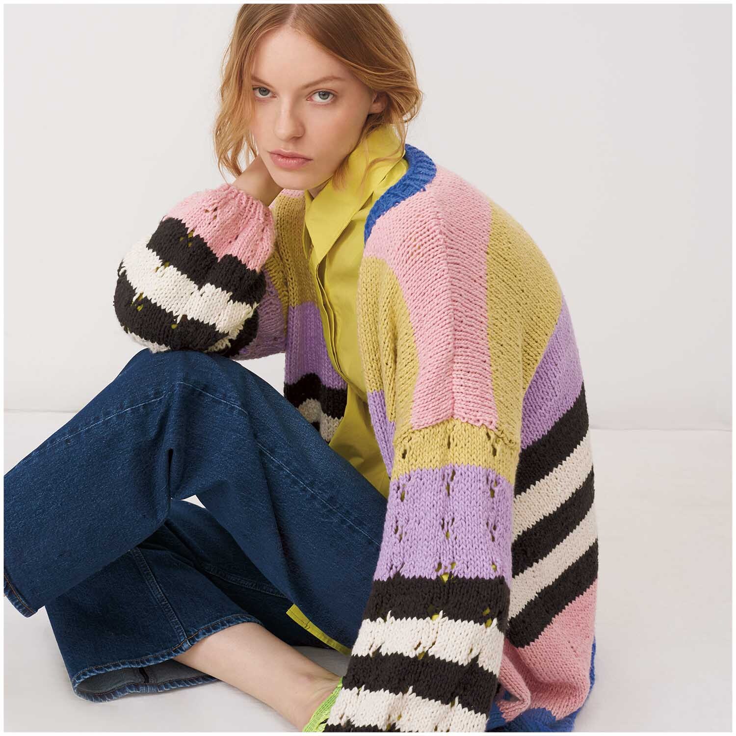 Creative So Cool + So Soft Cotton chunky 100g 100m Farbe Rosa von Rico Design Creative So Cool + So Soft Cotton chunky: Frau in bunter Strickjacke mit Streifenmuster, sitzt auf dem Boden.