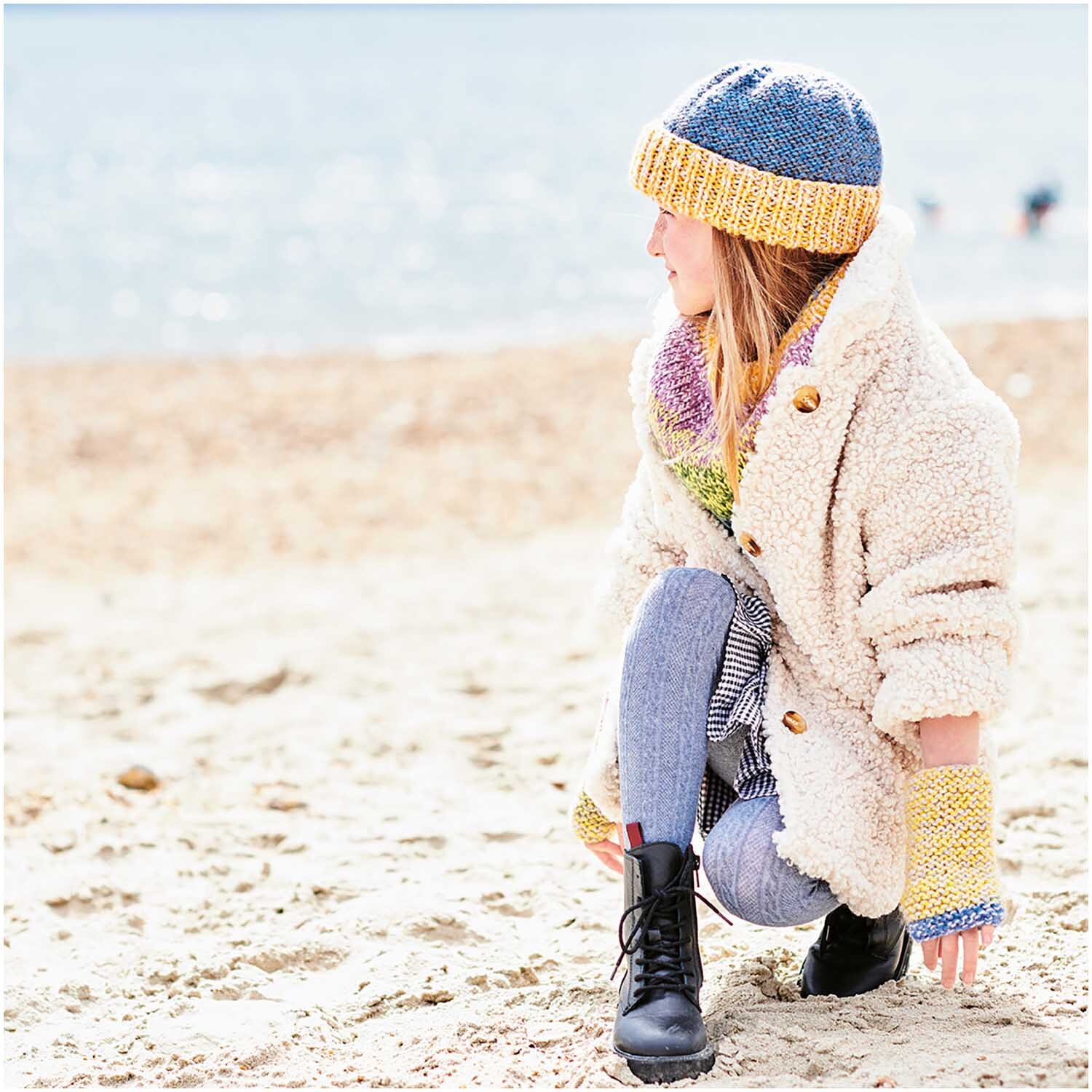 Creative Chic-Unique: Person am Strand in bunter Strickmütze und Schal von Rico Design, warm gekleidet.