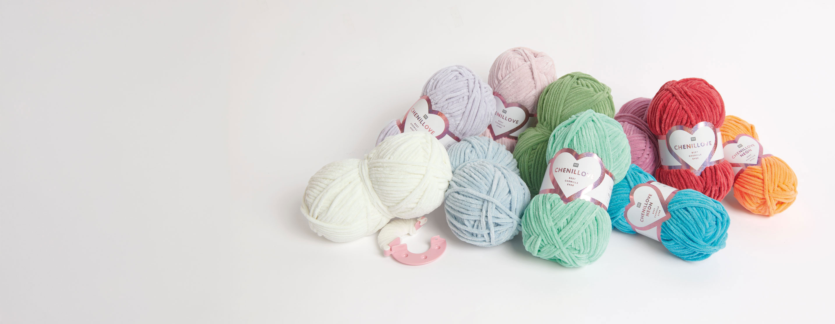 Viele bunte Chenillove Knäuel liegen zusammen auf einem grauen Untergrund