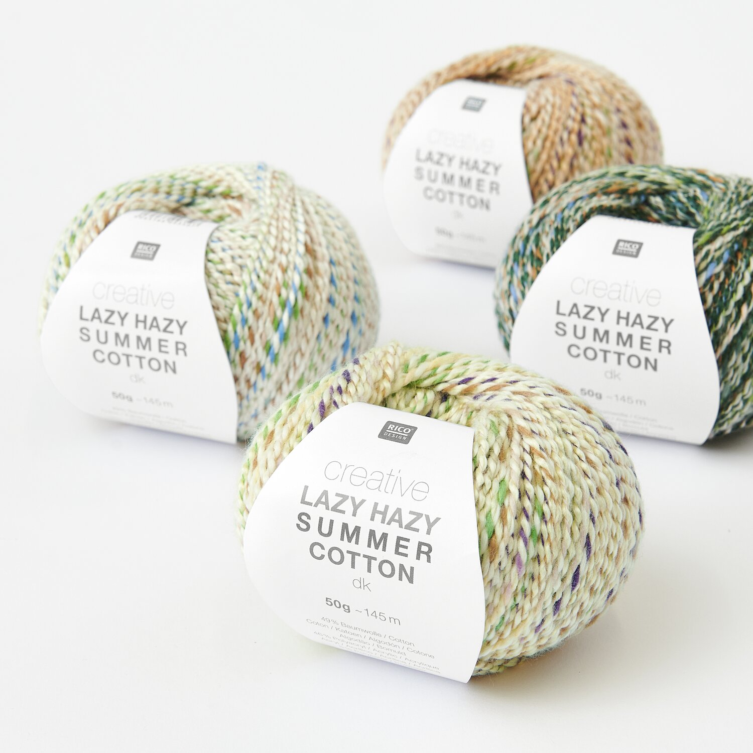 Creative Lazy Hazy Summer Cotton dk Sortiment zeigt vier bunte Garnknäuel in Zitrone, Elfenbein, Pfirsich und Efeu.