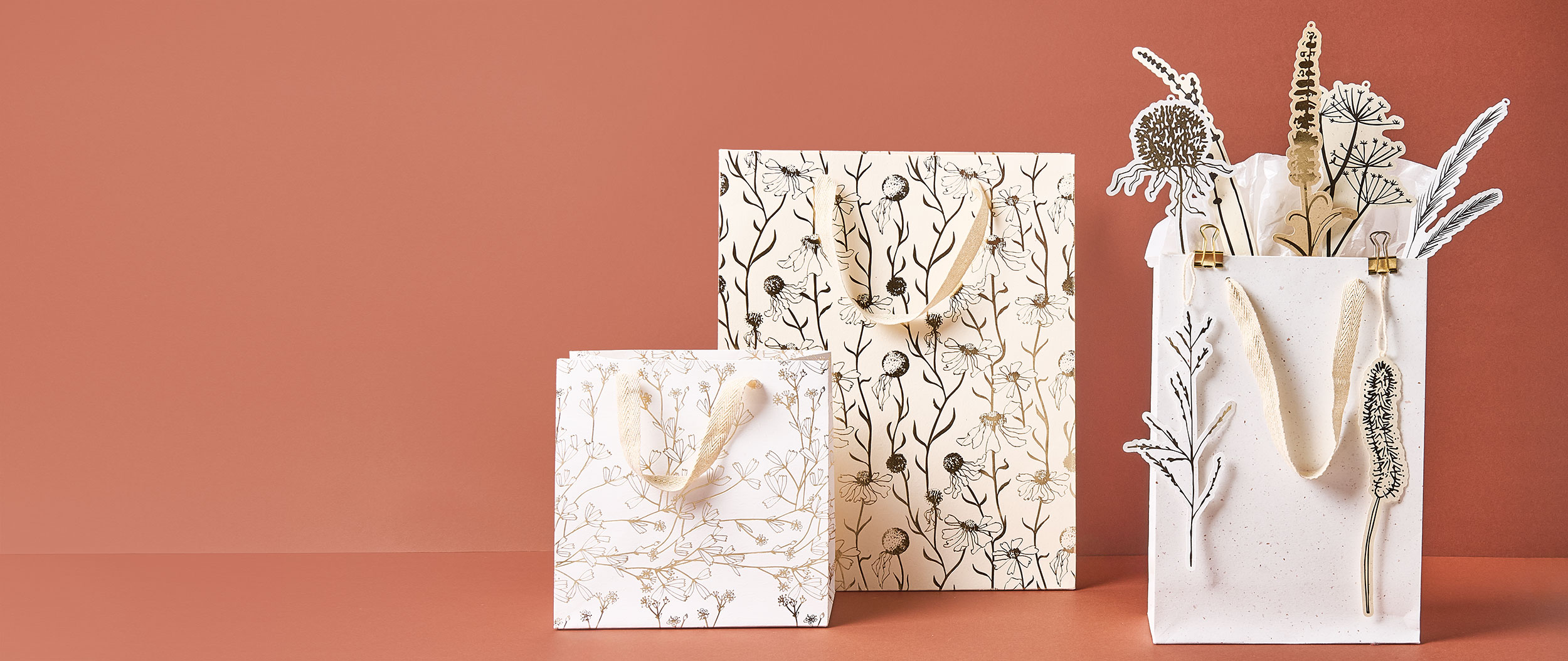 Drei Geschenktüten in unterschiedlichen Größen und Motiven, dazu verschiedene Geschenkanhänger. Produkte aus der Kollektion In The Meadow.