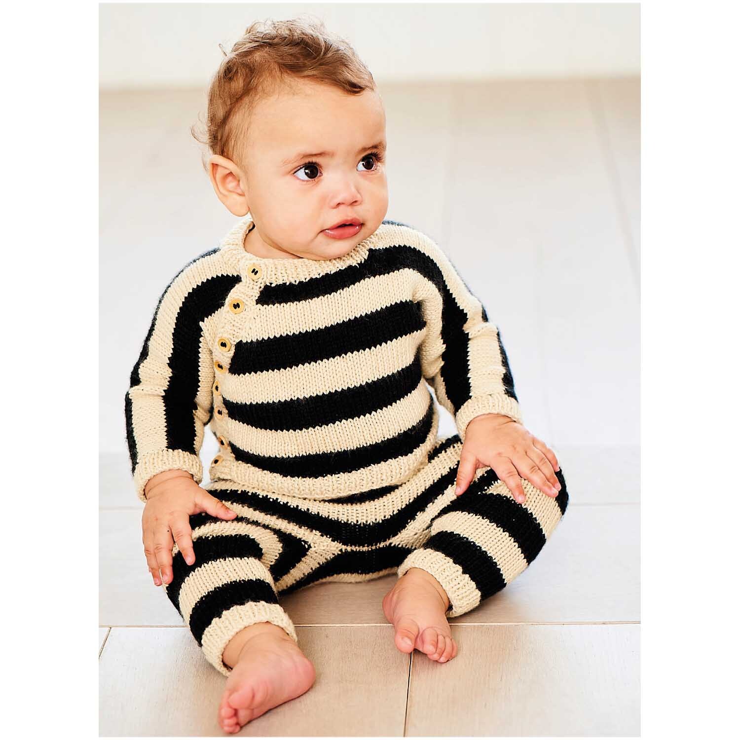 Rico Baby Dream dk uni - A Luxury Touch: Baby in gestreiftem Strickanzug aus weichem Garn, sitzend auf hellem Boden.