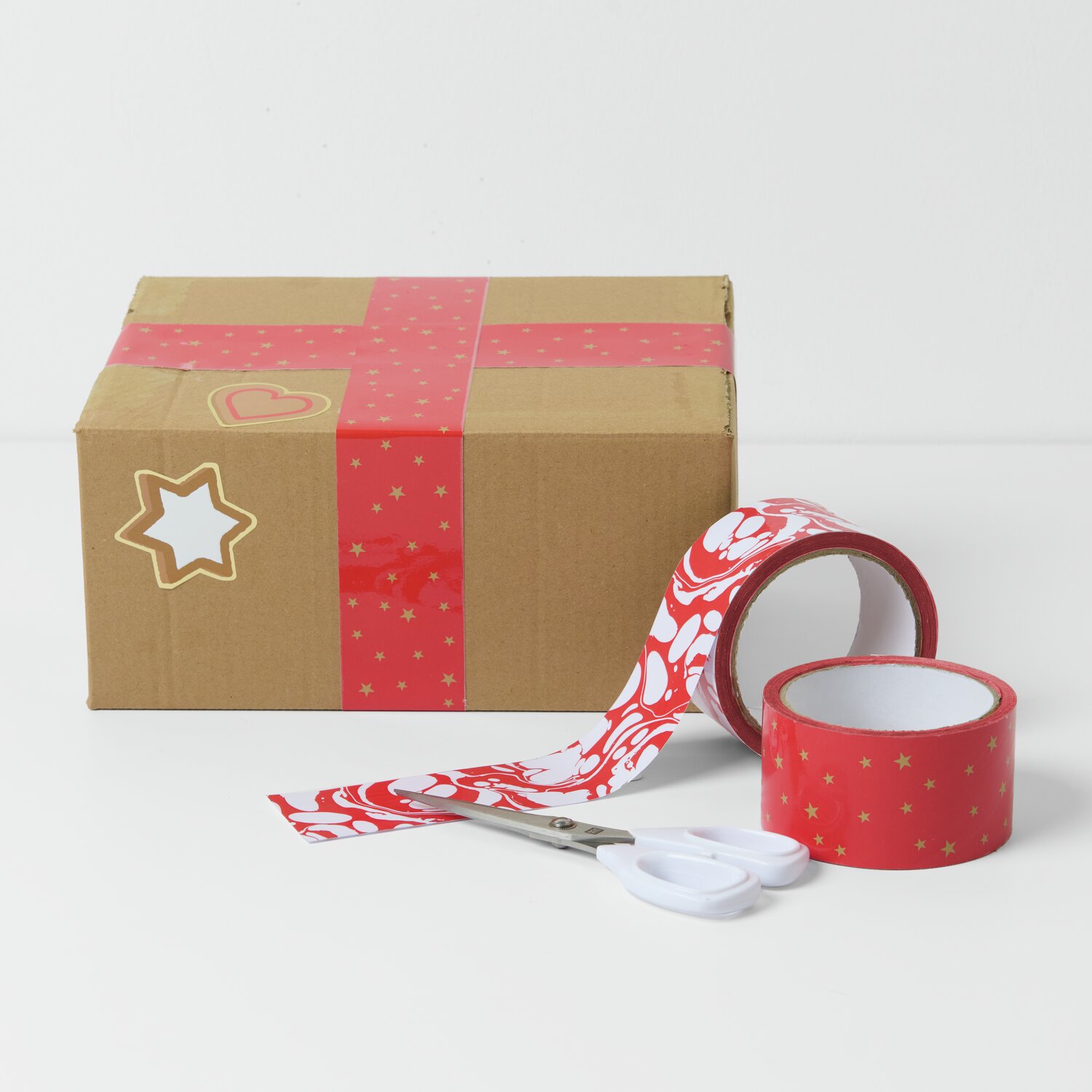 Paketklebeband Weihnachtsmarkt 5cm, rot-weiß marmoriert, dekoriert ein Paket mit Sternenmotiv. Ideal für festliche Verpackungen.