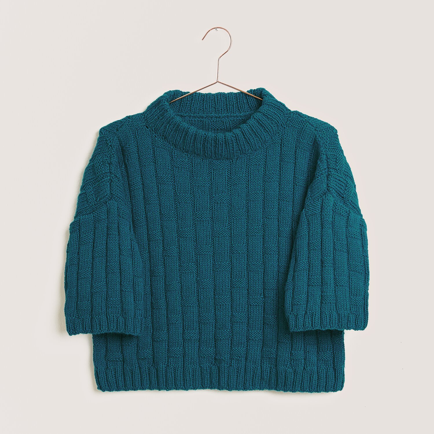 Strickset Shirt Modell 12 aus Made by Me Nr. 18 in Petrol, gestrickt aus Creative Cotton Fleece dk, präsentiert auf einem Kleiderbügel.