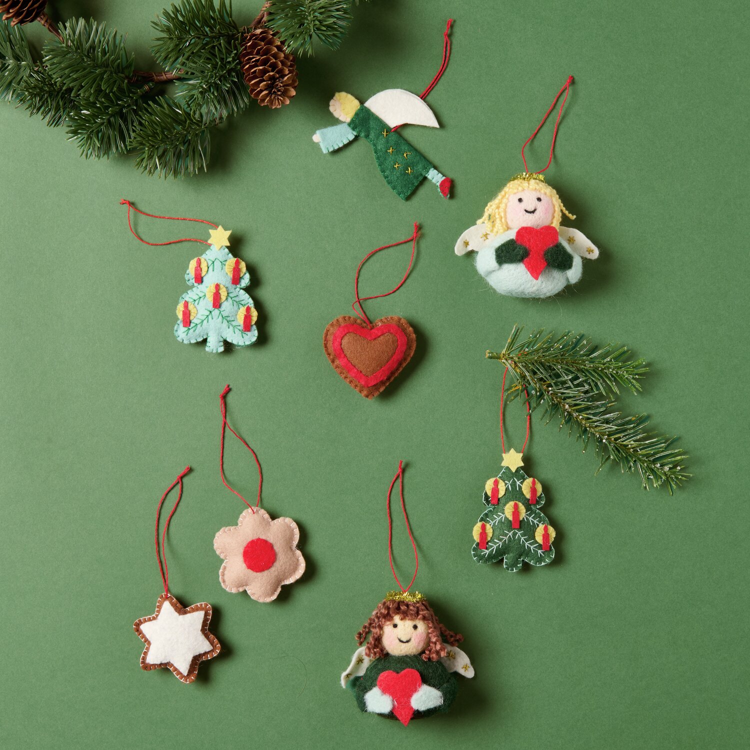 Aufhänger Filz-Engel flach Grün: Filz-Engel in Grün mit Flügeln, umgeben von weiteren bunten Filzdekorationen auf grünem Hintergrund.