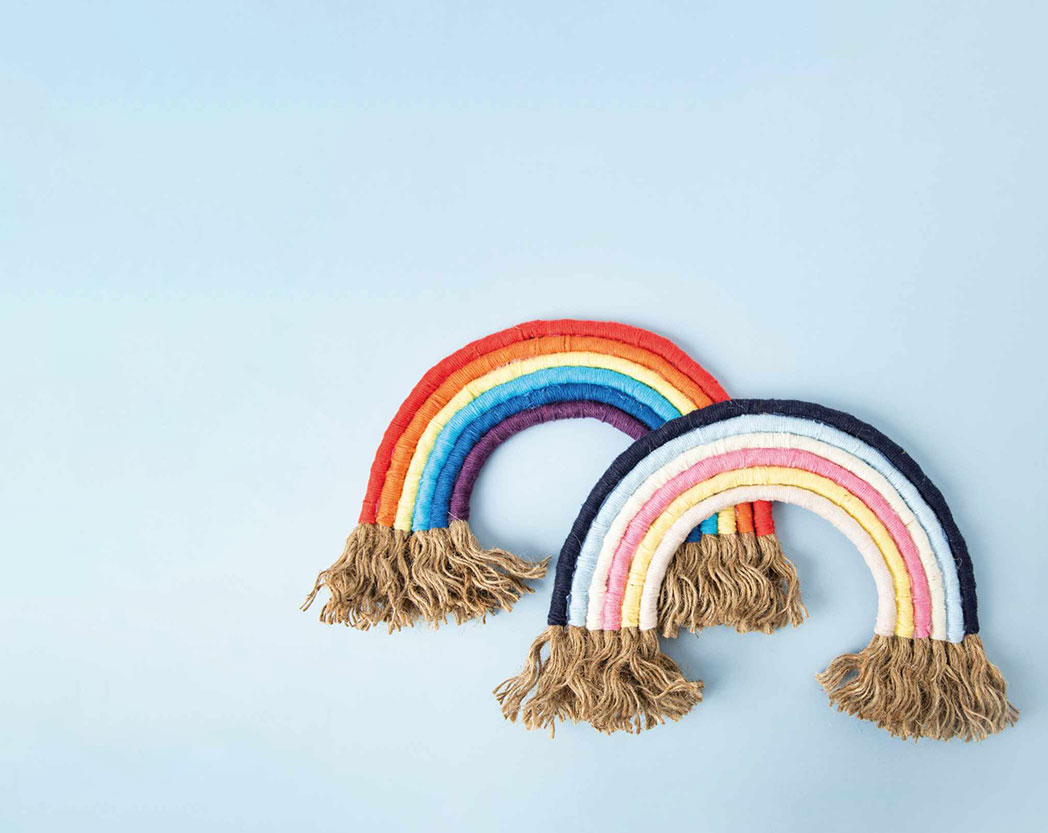 Zwei Regenbögen, einer in bunten- und einer in pastellfarben, leicht übereinandergelegt. Flatlay von Produkten.