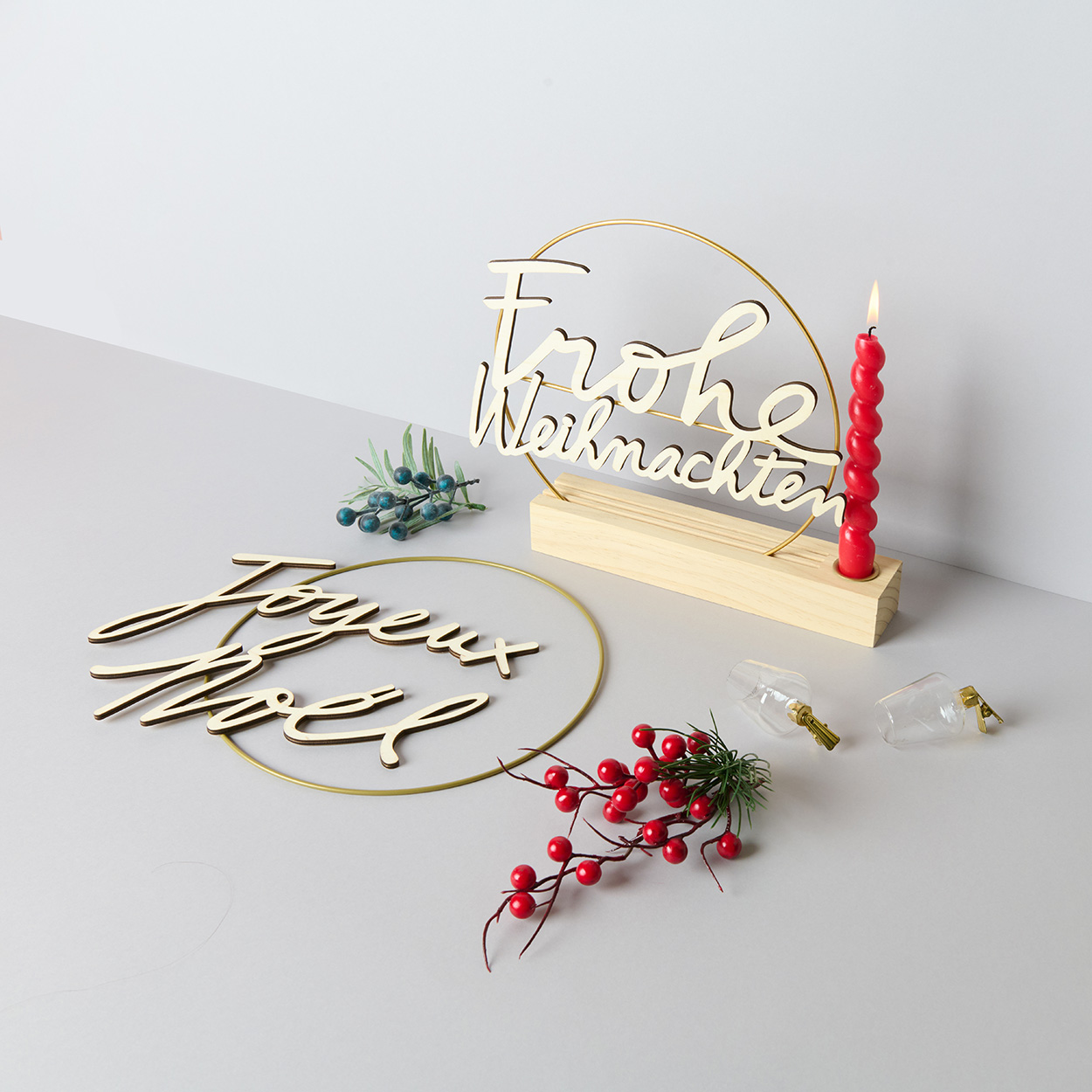 Dekoringe mit weihnachtlichem Schriftzug und Zweigen. Fotosetting graue Ecke.