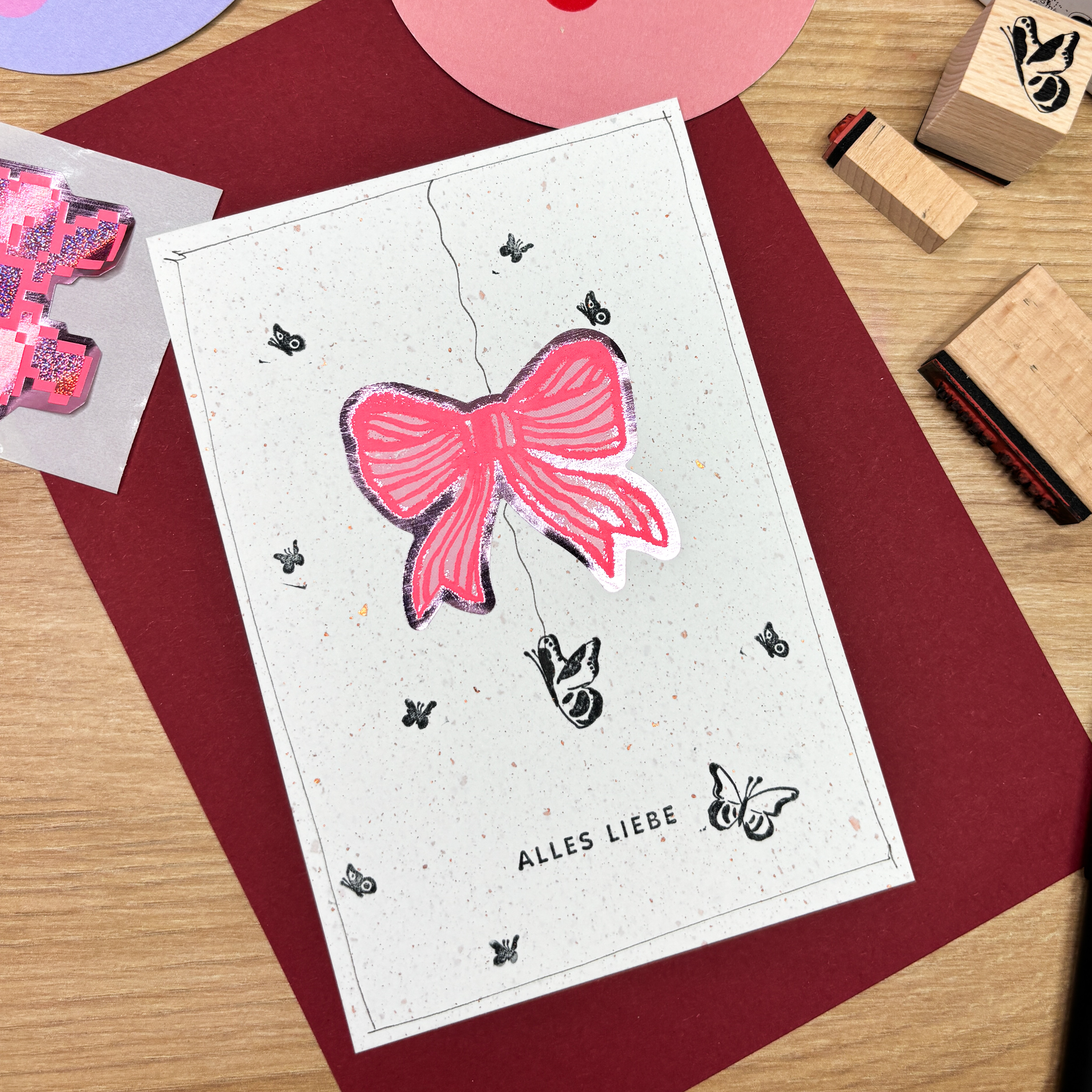 Eine Karte mit einem pinken Schleifen-Sticker und kleinen gestempelten Schmetterlingen und einem Schriftzug.