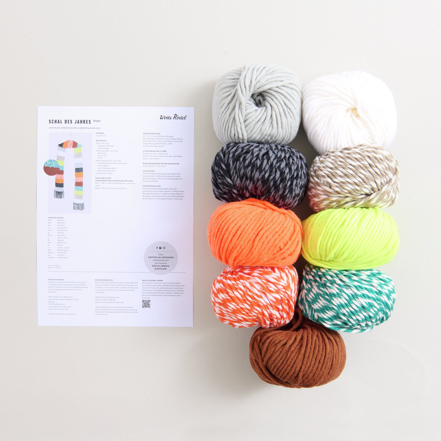 Garnset „Schal des Jahres“ mit bunten Wollknäueln und Anleitung von Wolle Rödel auf hellem Hintergrund.