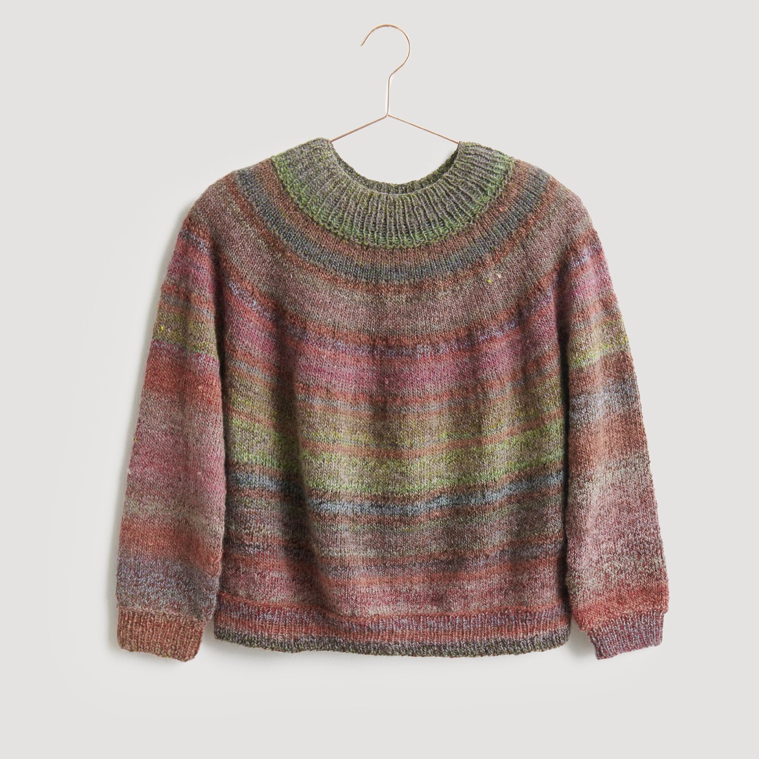 Lovewool No. 21 Herbst-Winter Sprachauswahl deutsch von Rico Design Pullover in sanften, mehrfarbigen Tönen, präsentiert auf einem Kleiderbügel. Der Strickpullover von Modell Legeware besticht durch sein einzigartiges Design und die harmonische Farbgebung. Ideal für kühle Tage.