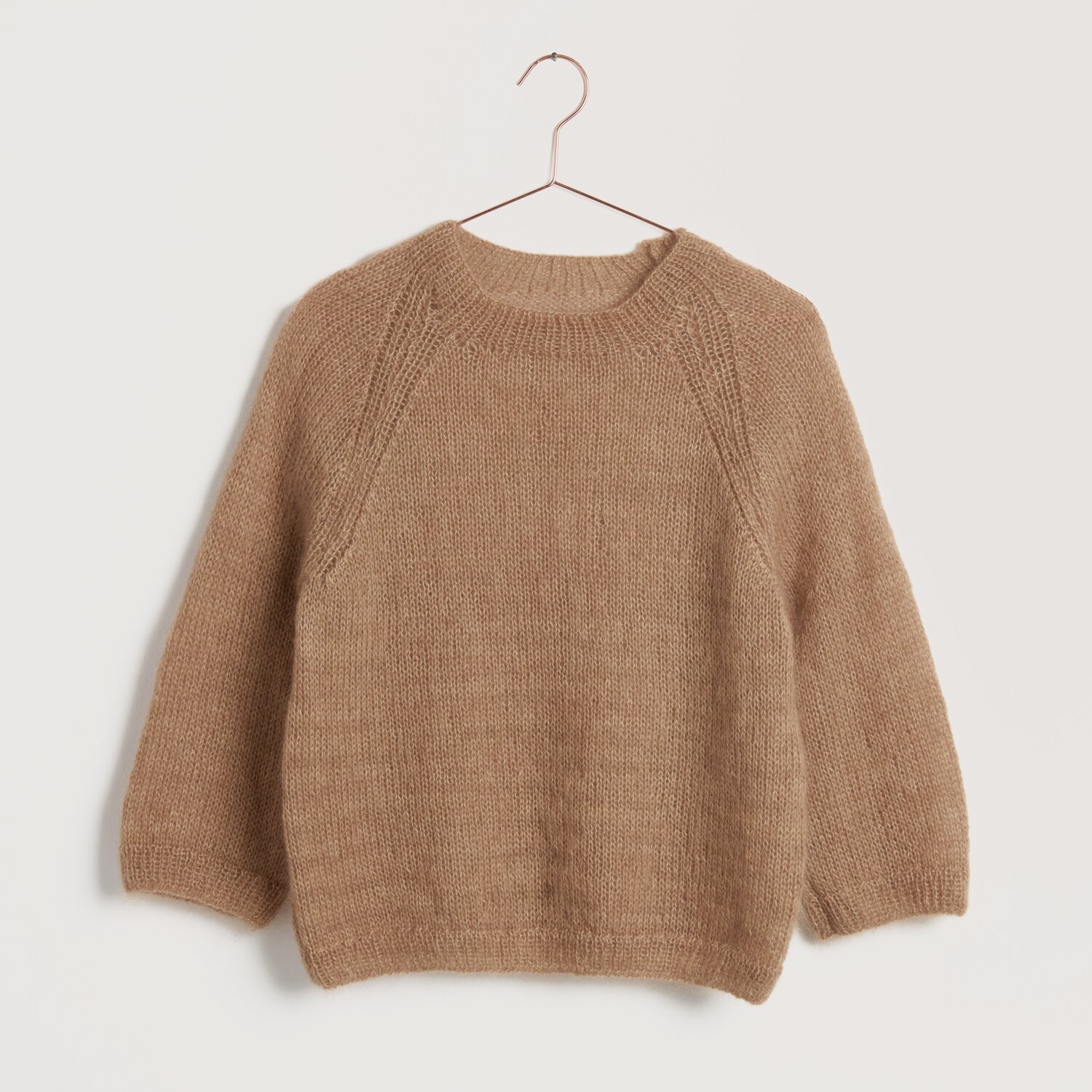 Strickset Pullover Modell 16 aus Lovewool No. 22 in Nougat auf einem Kleiderbügel vor neutralem Hintergrund.