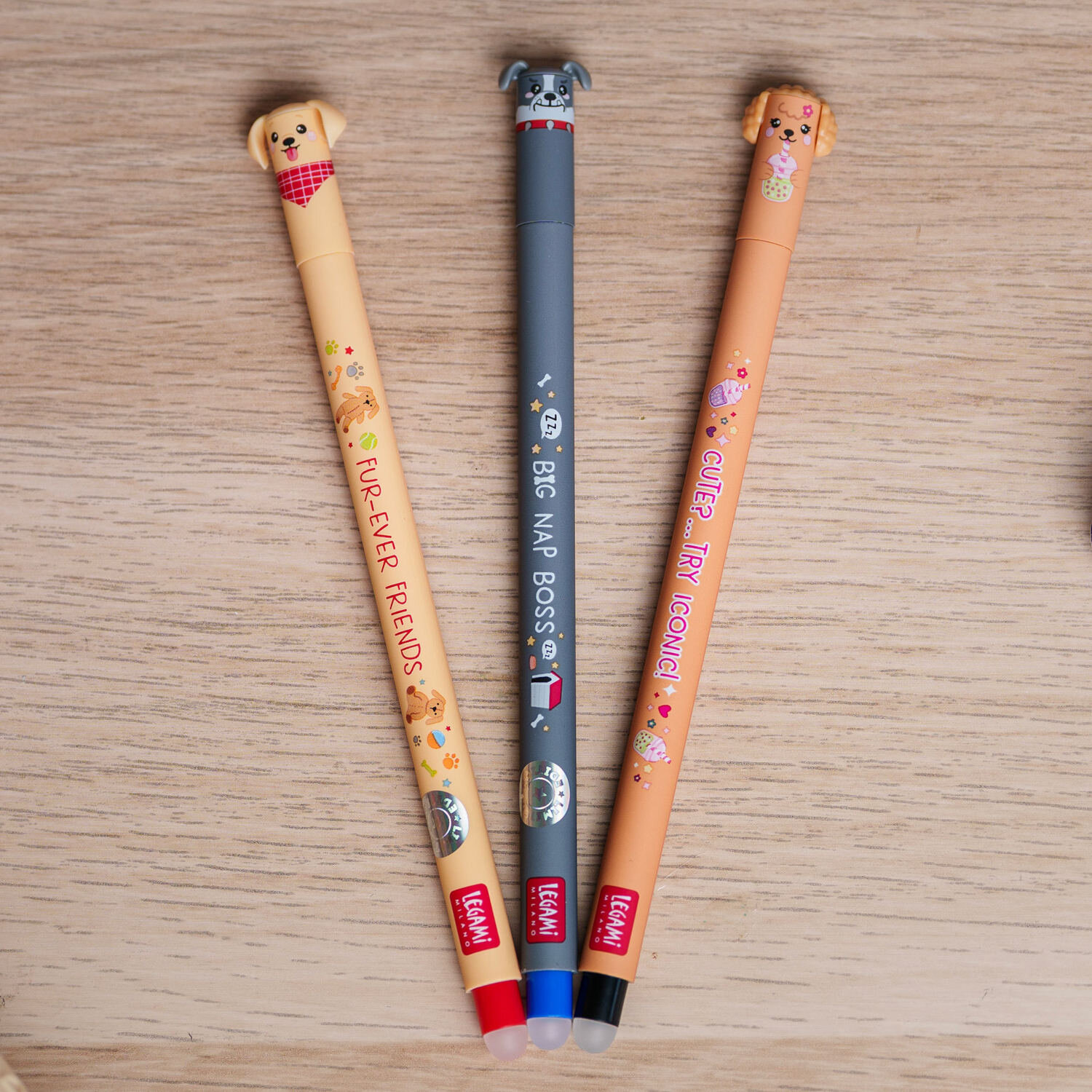 Erasable Gel Pen Set 3 Stück Fur-ever Friends BTS 26 mit drei farbigen Legami Gelstiften, Hunde-Motiven und Radierkappen, dekorativ auf Holzoberfläche platziert