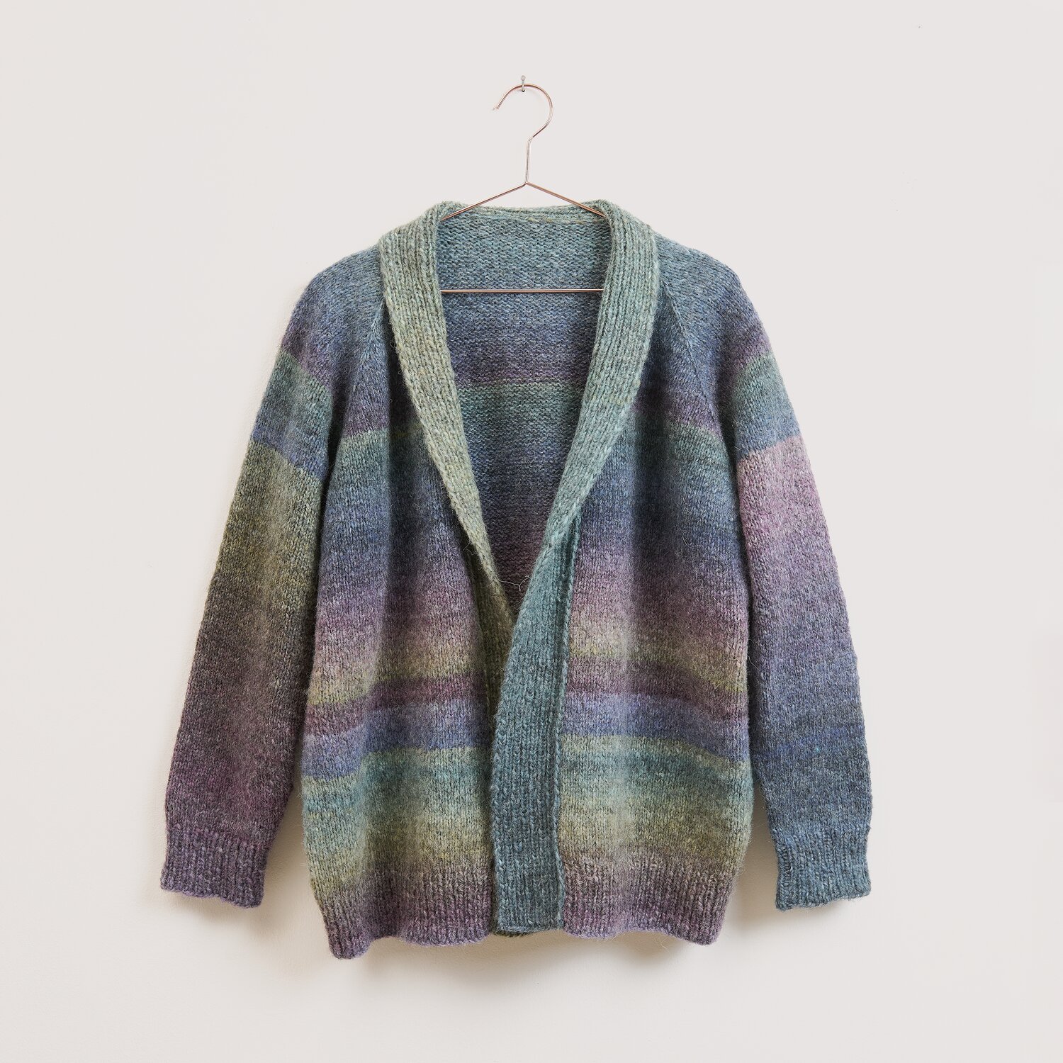Strickset Jacke Modell 22 aus Die Neue Masche No. 16 zeigt eine locker geschnittene, mehrfarbig melierte Strickjacke mit Schalkragen von Wolle Rödel am Bügel.