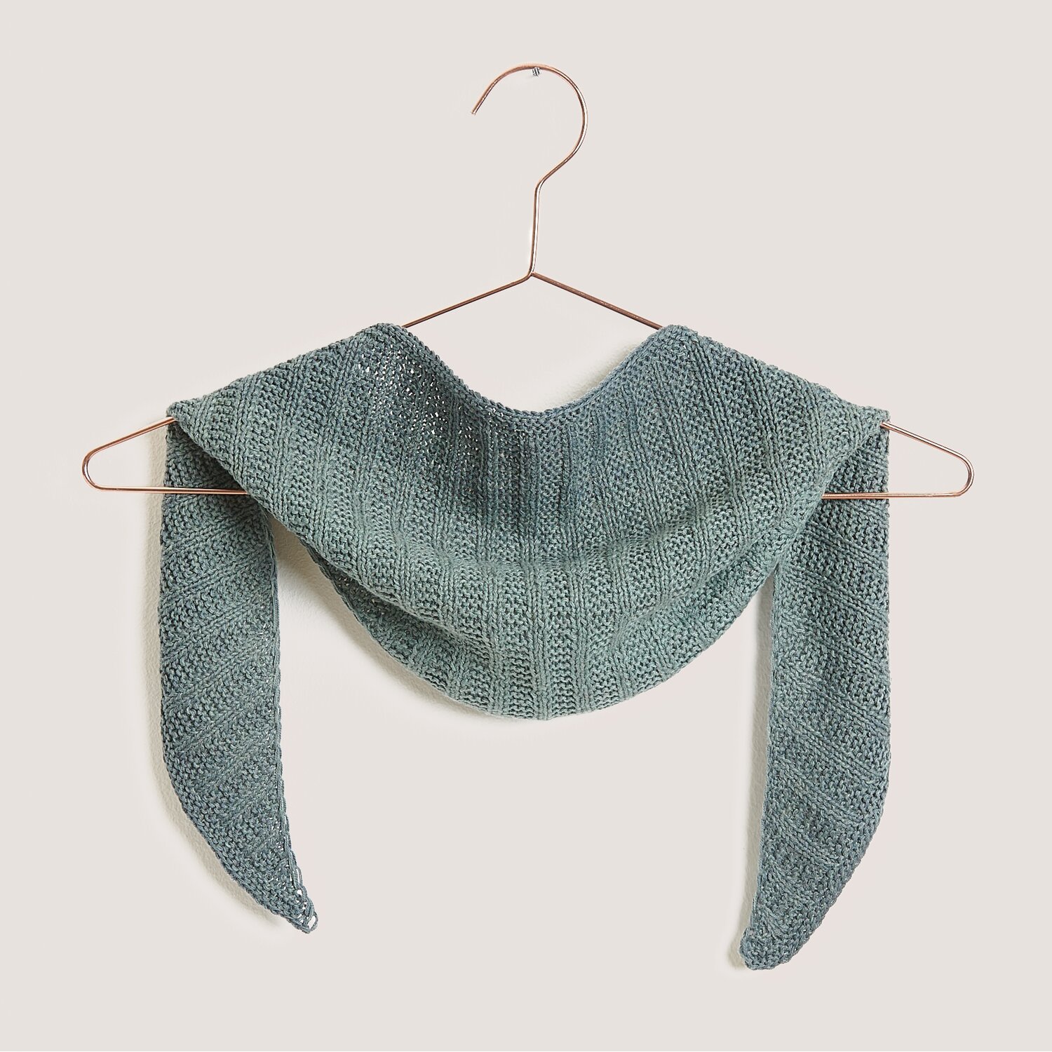 Strickset Dreieckstuch Modell 14 in Efeu auf einem Kleiderbügel, gestrickt aus Creative Cotton Dégradé Lucky 8.