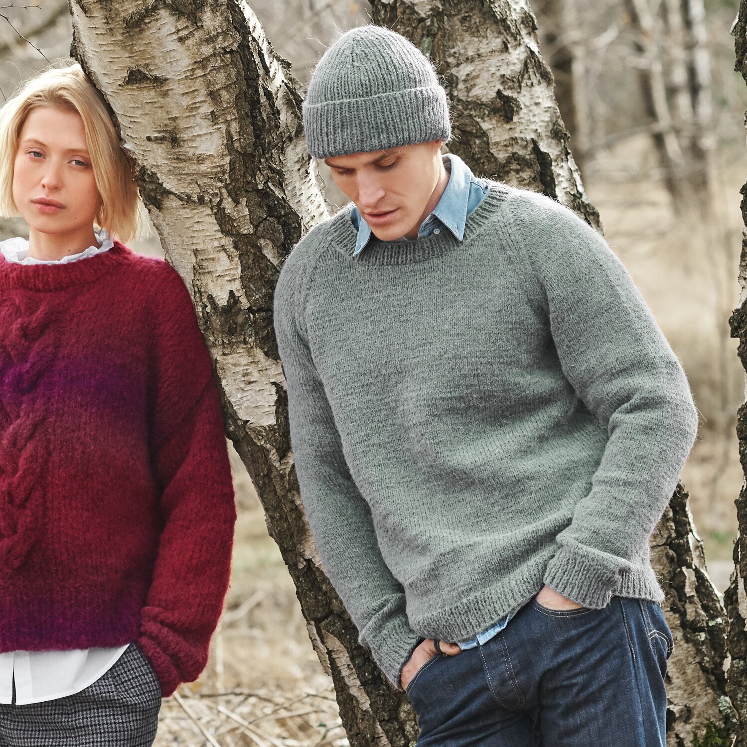 Strickset Pullover Herren Modell 18 aus Lovewool No. 21 von Rico Design Strickset Pullover Herren Modell 18 aus Lovewool No. 21: Grauer Pullover und Mütze, getragen von einem Mann im Freien neben einer Frau im roten Pullover.