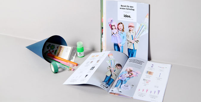 idee. Prospekt liegt in grauer Ecke mit Schultüte daneben