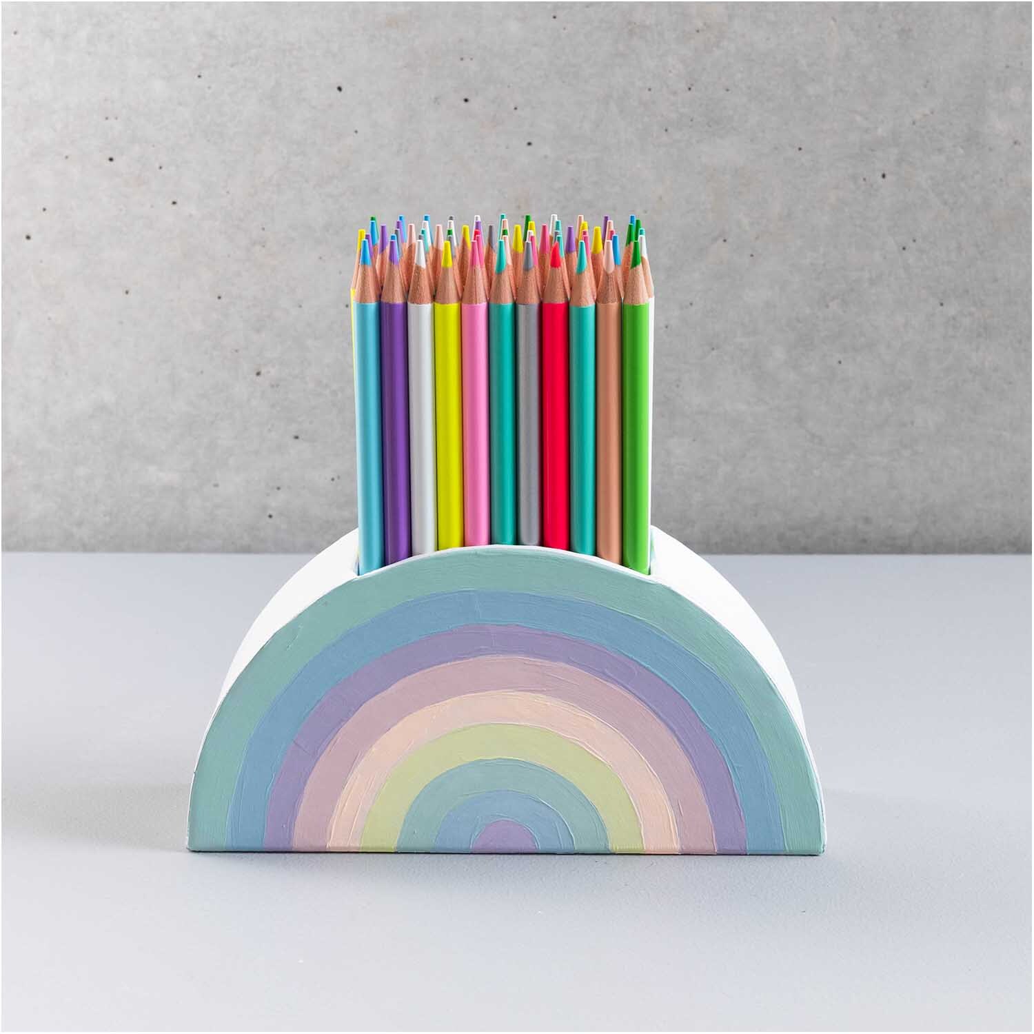 Stiftehalter aus Pappe halbrund 18x9x5cm Farbe Weiß von Rico Design Stiftehalter aus Pappe halbrund mit bunten Buntstiften, von Rico Design, vor grauem Hintergrund.