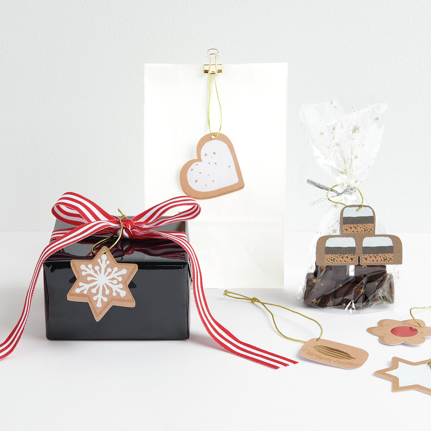 Paper Poetry Geschenkanhänger Cookies, 8-teilig, dekoriert auf Geschenken mit roten Schleifen.