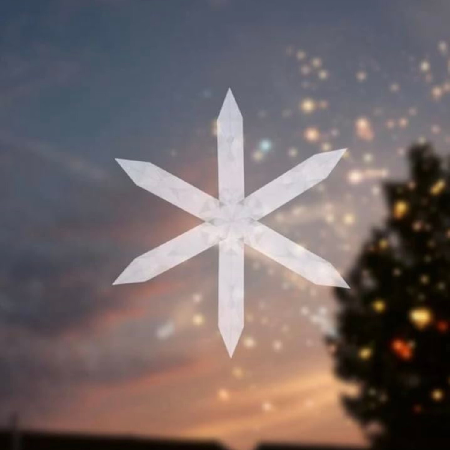 Schneekristalle aus Transparentpapier vor einem stimmungsvollen Abendhimmel mit Lichtern.