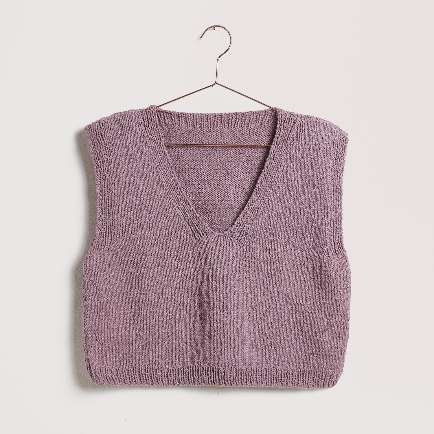Die Neue Masche No. 12 Frühjahr-Sommer von idee. Creativmarkt Strickset Top Modell 05b aus Die Neue Masche No. 12 in Mauve, präsentiert auf einem Kleiderbügel.