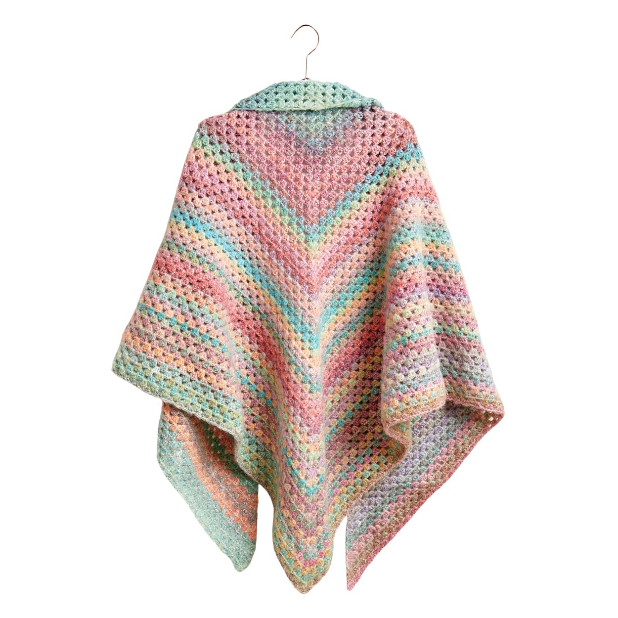 Ein gehäkelter Poncho in bunten Farben hängt an einem Kleiderbügel.