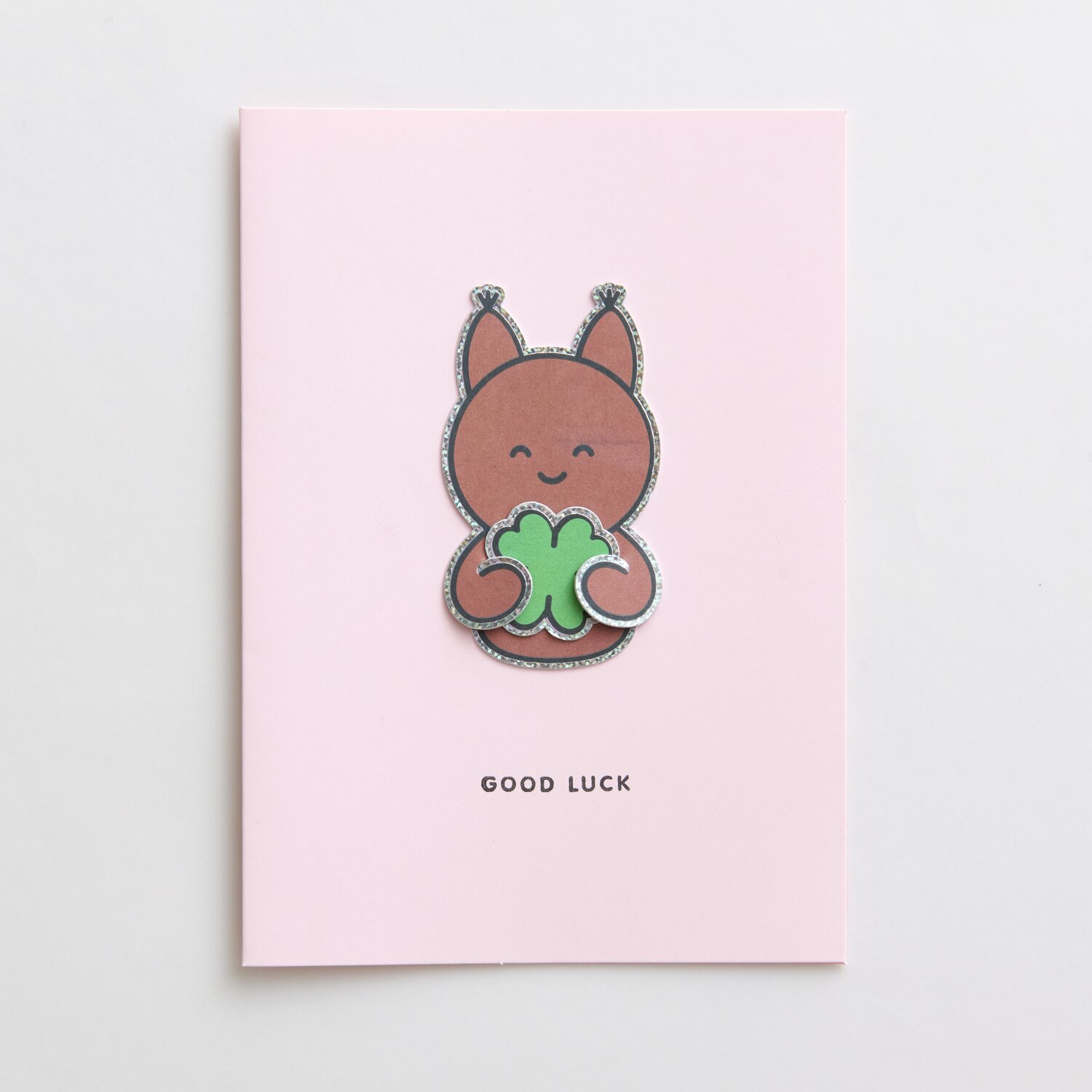 Paper Poetry Clip-Ons Chingu Tiere: Rosa Karte mit niedlichem Tiermotiv und Kleeblatt, "Good Luck" Text.