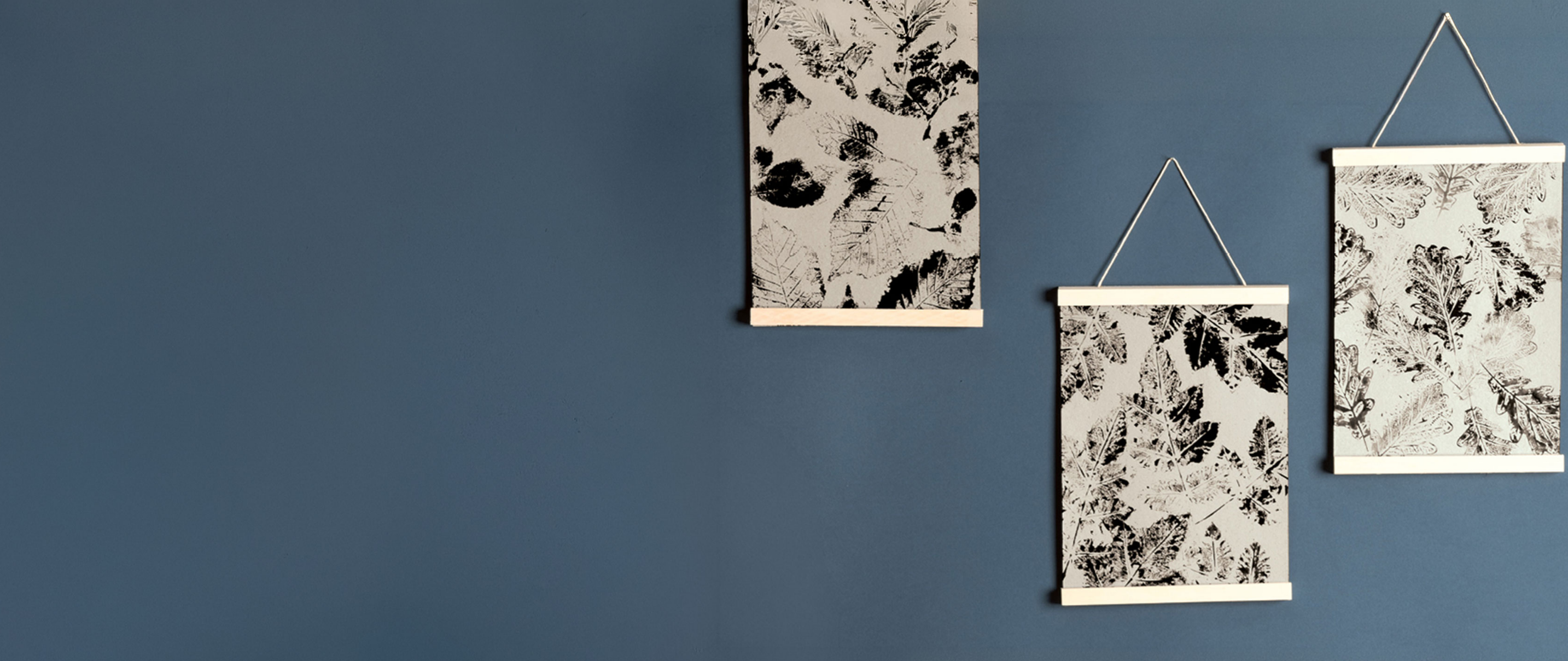 Selbst gestaltete Herbstbilder mit Blattmotiven an einer blauen Wand aufgehängt.