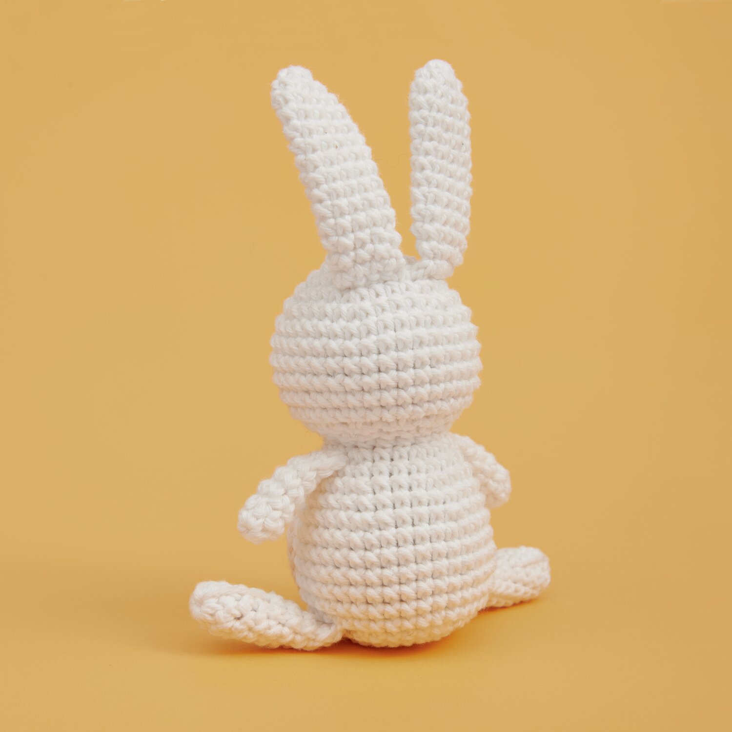 Ricorumi Mini Easy Häkelset - Häschen: Weißes gehäkeltes Häschen von Rico Design auf orangefarbenem Hintergrund.