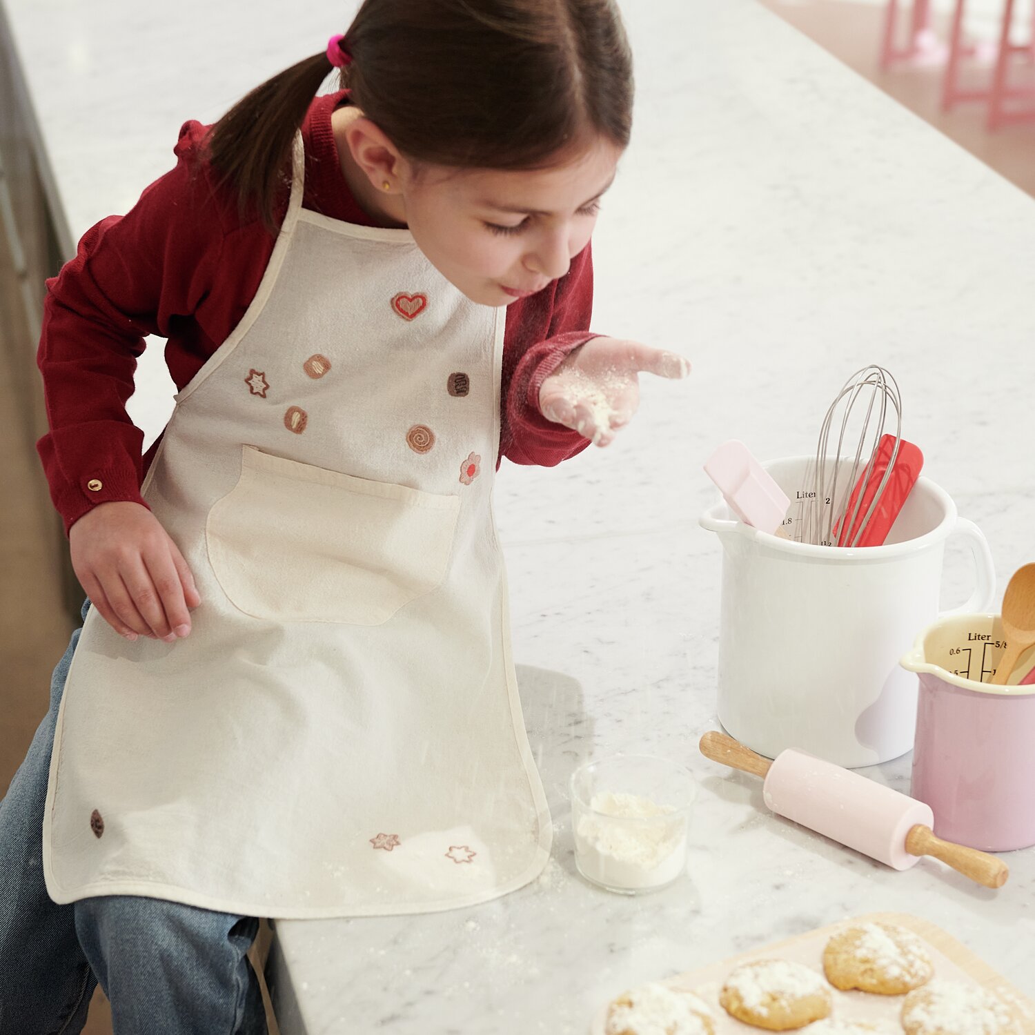 Stick & Stitch Stickpackung Kekse 23 Stück: Mädchen mit bestickter Schürze backt Kekse.