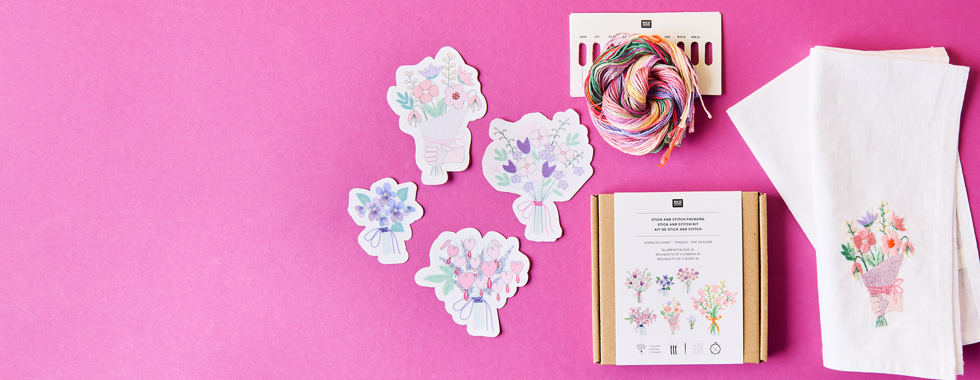 Ein Stick and Stitch Set aus der Kollektion The Sky Is The Limit mit floralen Motiven, daneben ein bereits bestickter Stoff. Flatlay von Produkten.