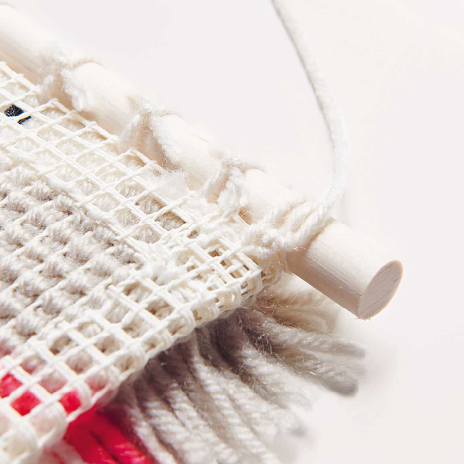 Holzstab ist am Stramin eines geknüpften Wandbehang befestigt