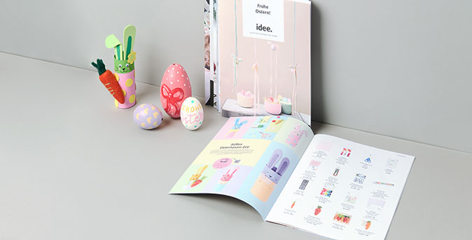 idee. Prospekt liegt in grauer Ecke mit Osterdeko daneben