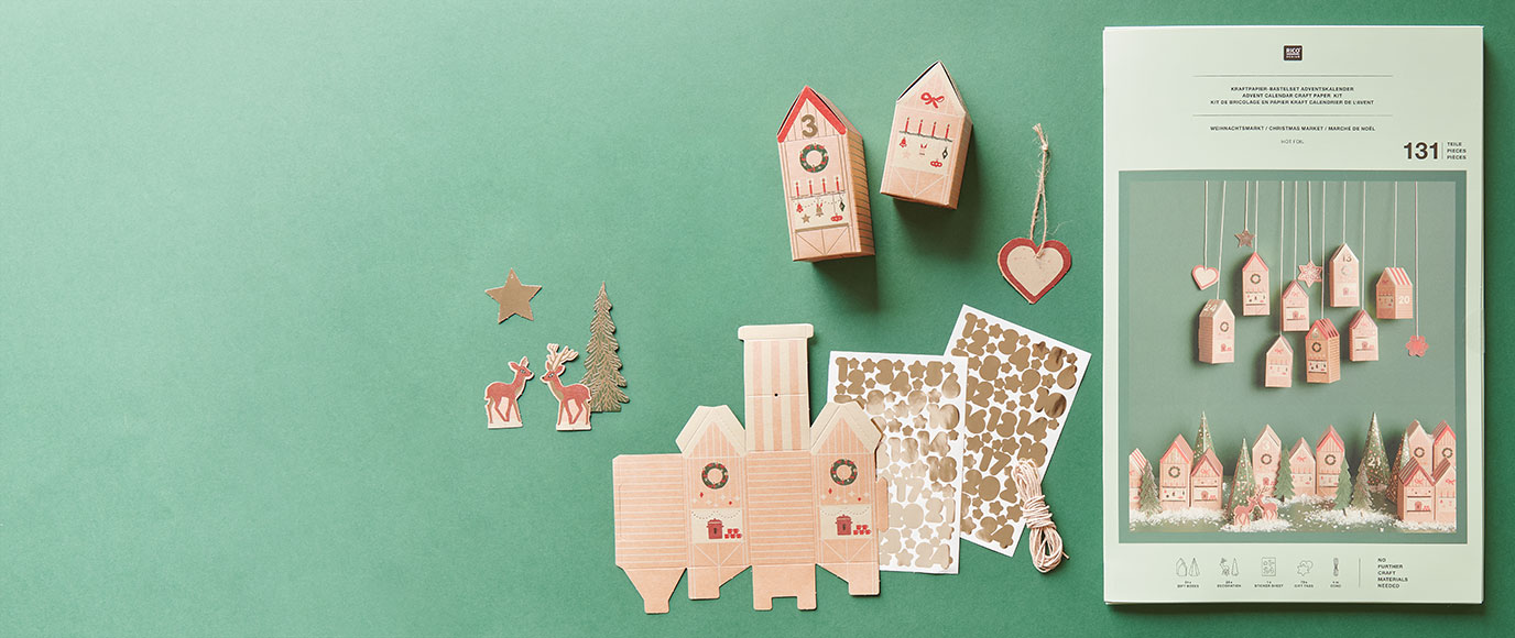 Adventskalender Bastelset mit Papphäusern und Zahlenstickern. Ein Adventskalender Bastelset mit Schachteln in Hausform und Zahlen-Stickern. Flatlay von Produkten.