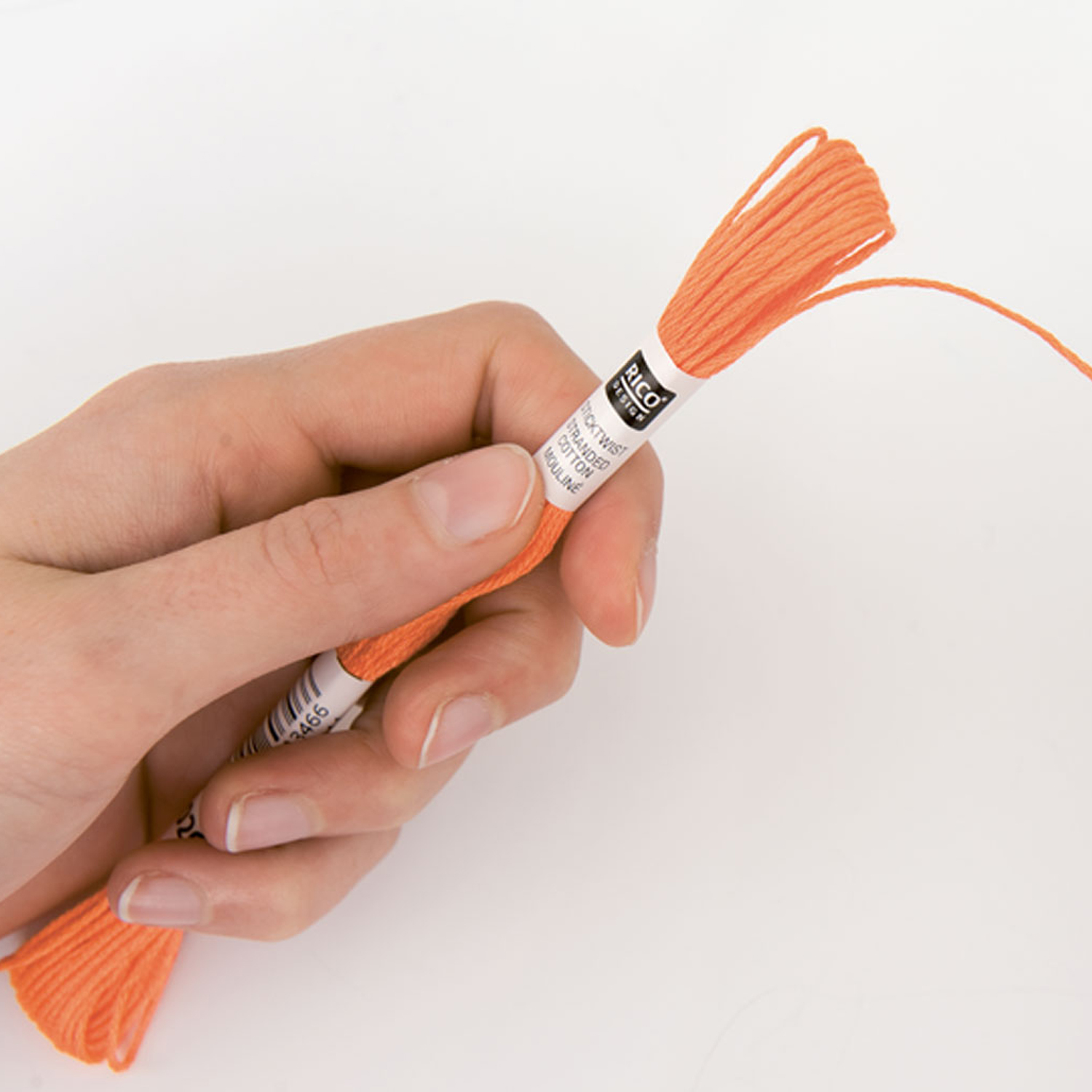 Eine Hand hält Sticktwist in Orange