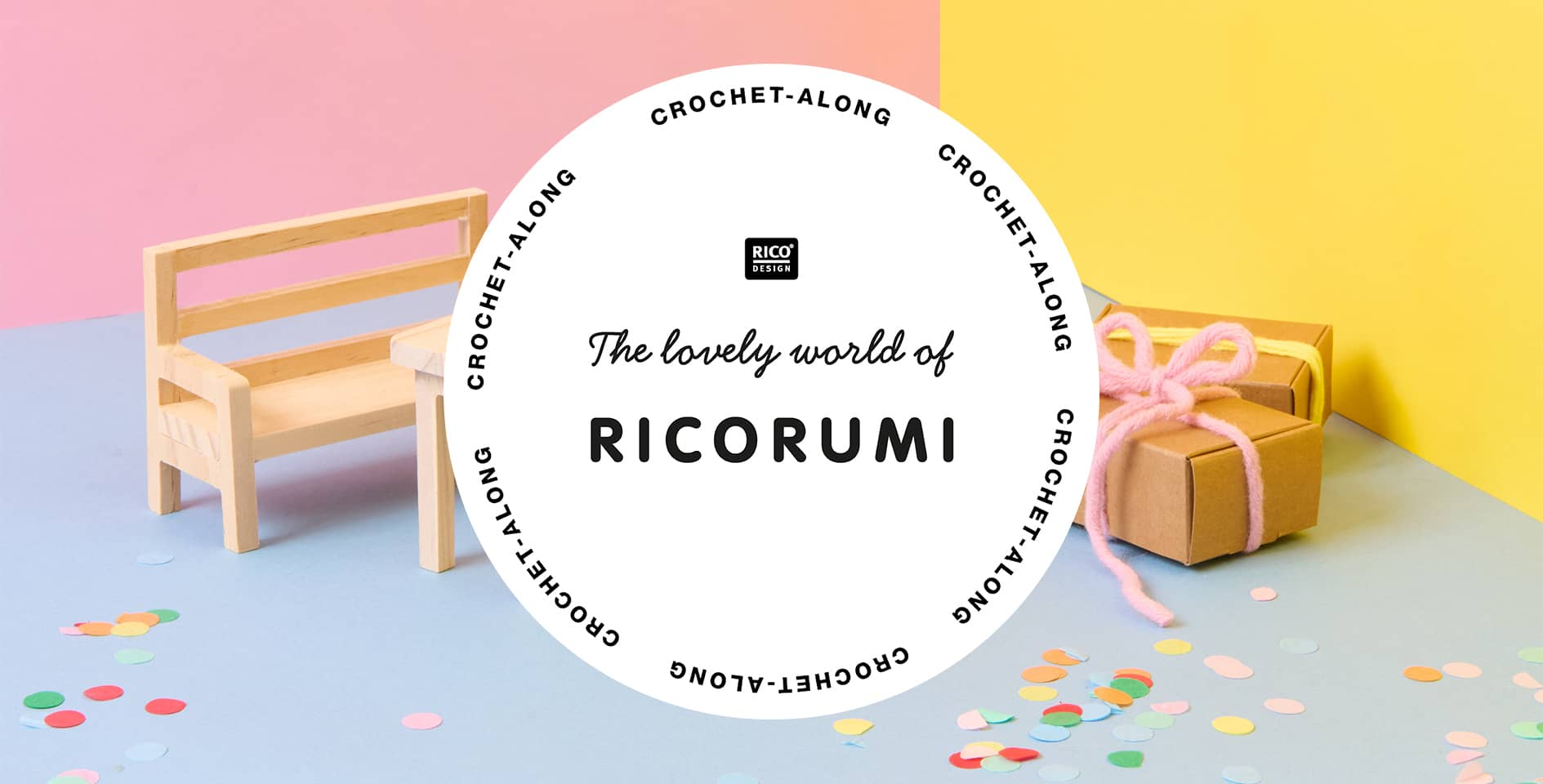 Eine Minaturwelt mit Miniatur-Möbeln und Geschenken ist vor bunten Wänden aufgestellt. Konfetti liegt auf dem Boden verstreut. Davor ein Logo von Ricorumi.