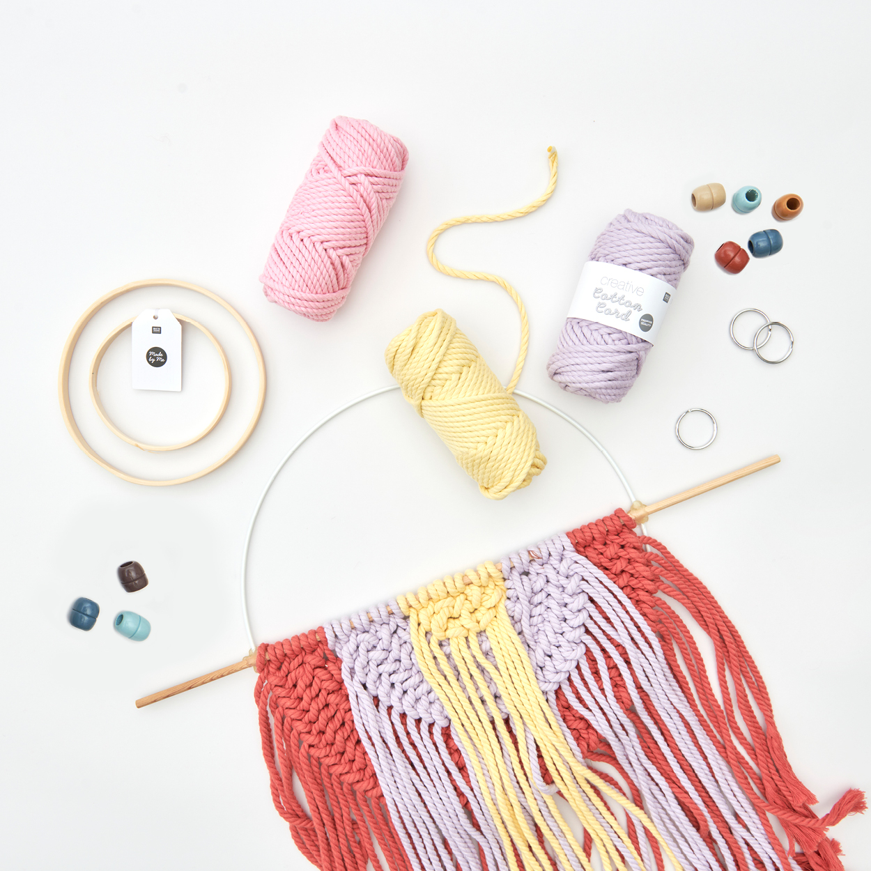 Ein runder Makramee-Wandbehang mit Kordel-Garn, Perlen und Holzringen. Flatlay von Produkten.