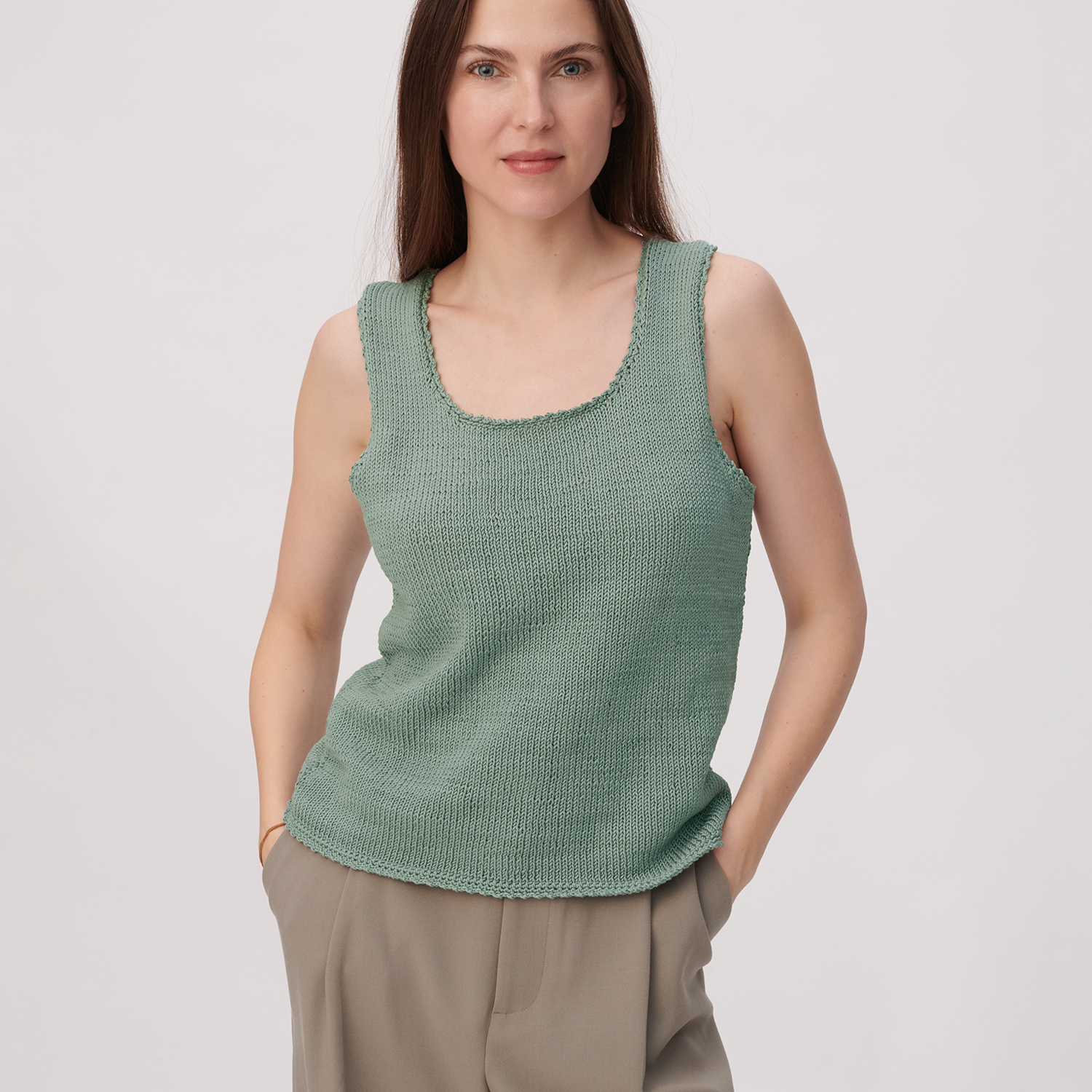 Strickanleitung Top mit Racerback aus Mille Fili Strickanleitung Top mit Racerback aus Mille Fili: Frau trägt grünes Stricktop, kombiniert mit beigen Hosen.