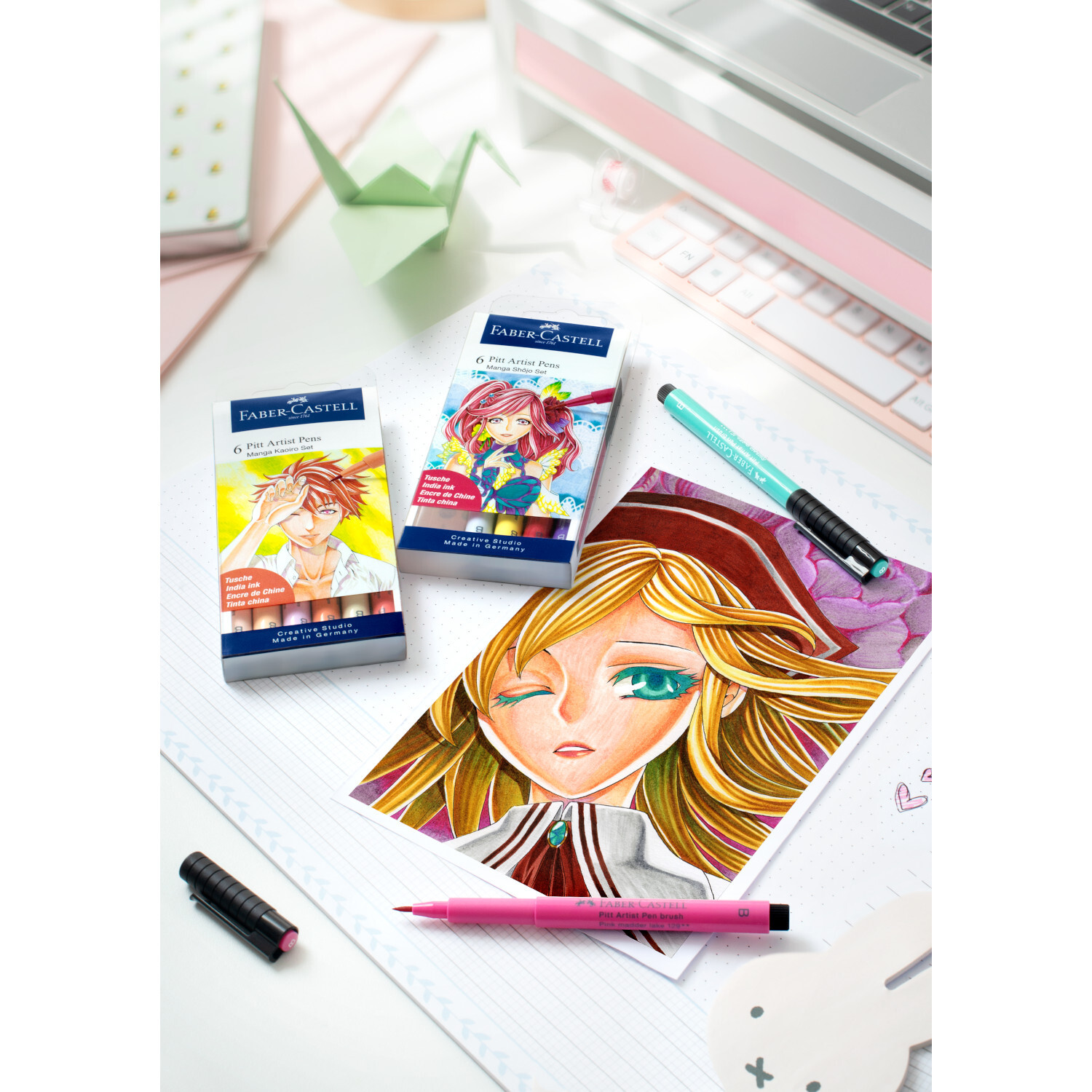 Pitt Artist Pen Manga Kaoiro Tuschestift-Set 6-teilig von Faber-Castell Pitt Artist Pen Manga Kaoiro Tuschestift-Set 6-teilig von Faber Castell auf Schreibtisch mit Manga-Zeichnung und Stiften in verschiedenen Farben.