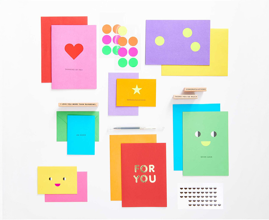 Bunte Karten mit Stickern, Stempeln, Stift und Gesichtern verziert, liegen über und nebeneinander. Flatlay von Produkten.