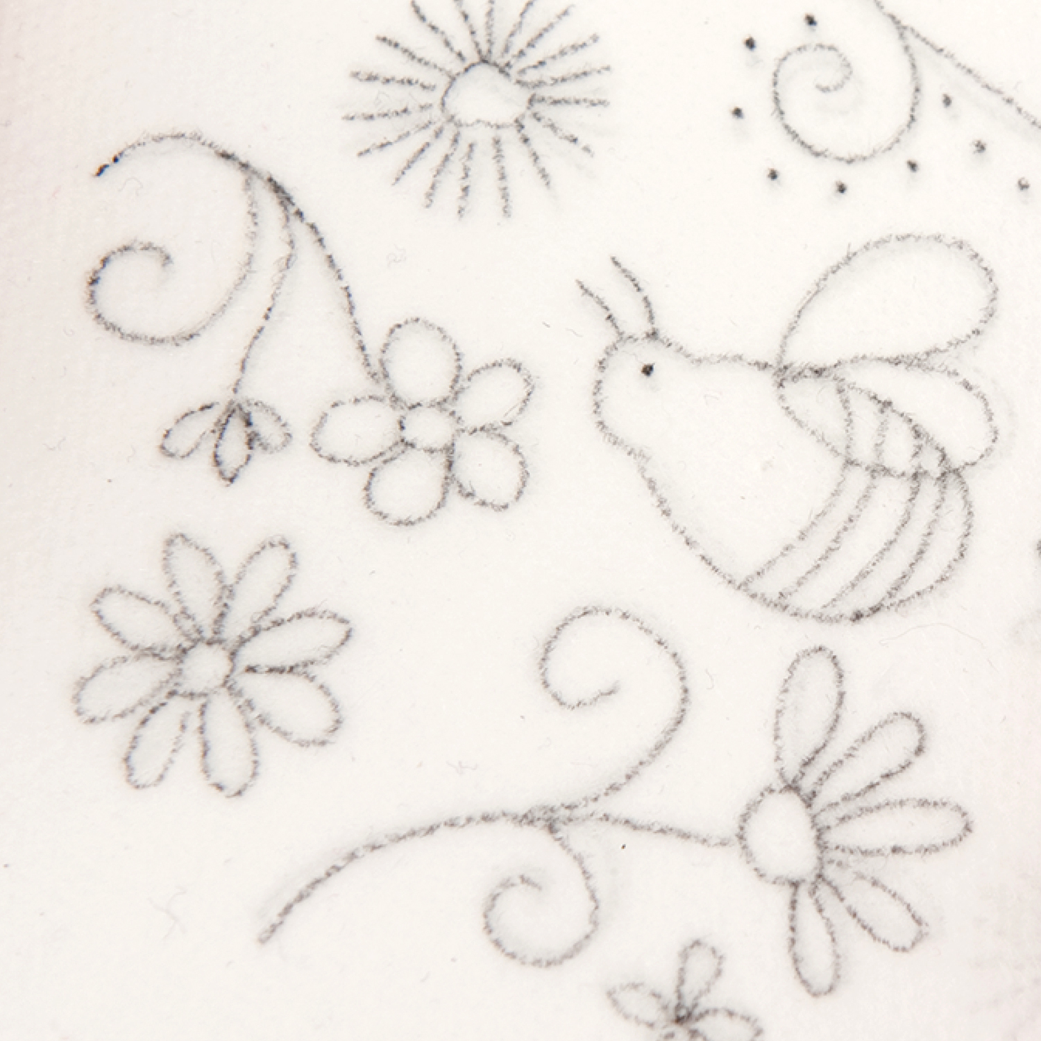 Eine Vorlage mit Bienen und Blumen-Motiv wird mit einem Bleistift auf Solufix Vlies übertragen